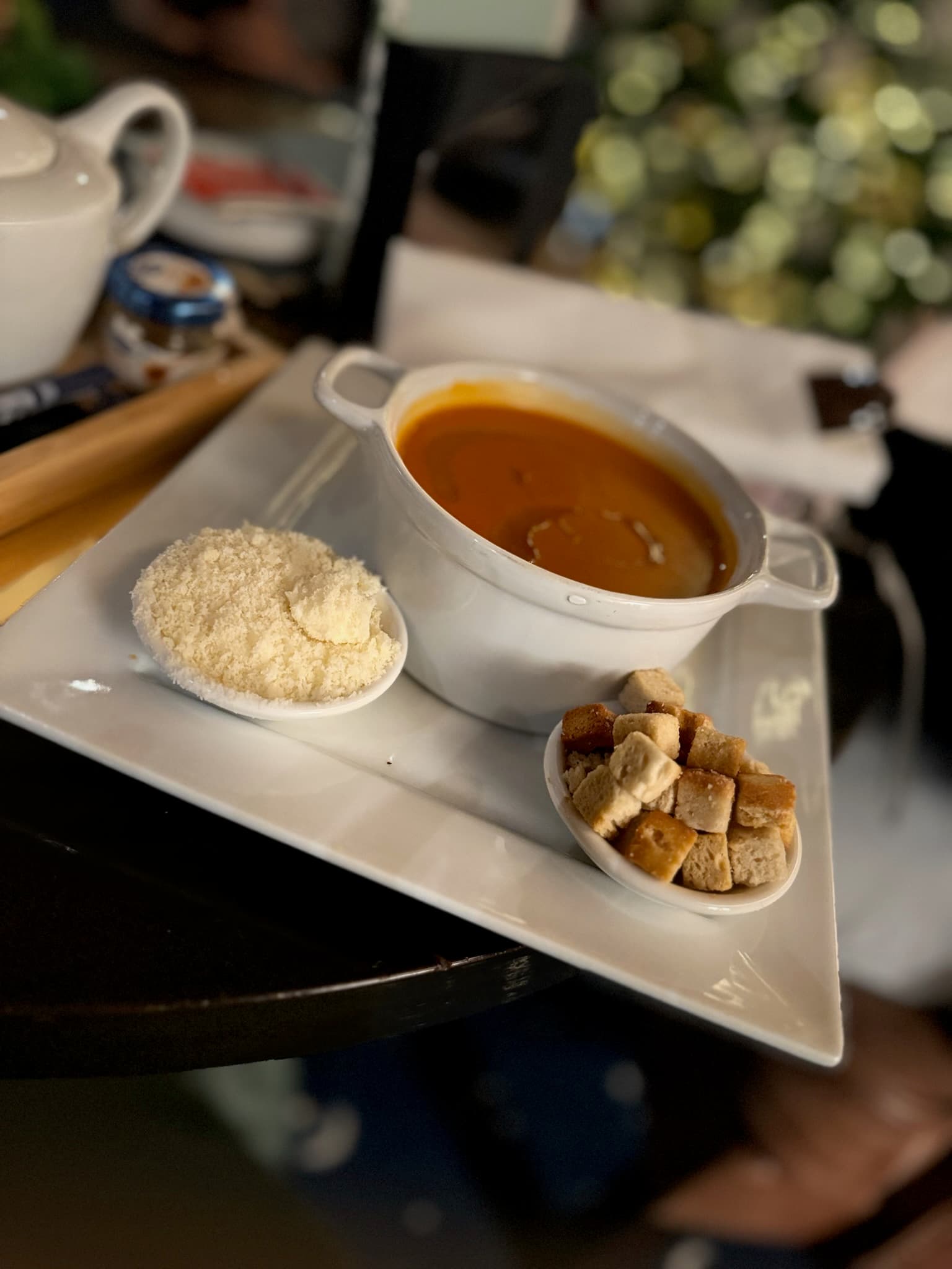 A white plate with a cup of soup.