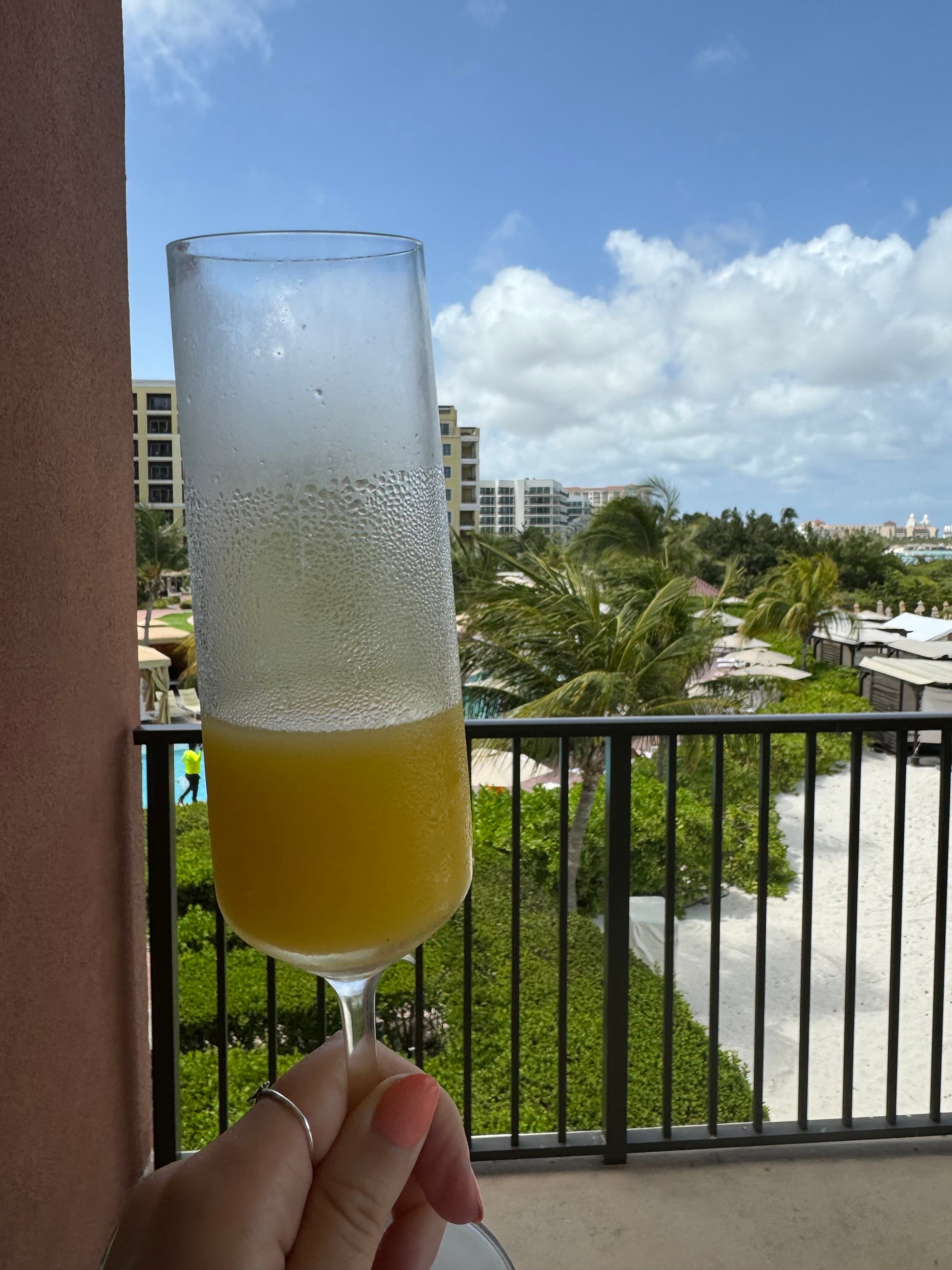 A hand holding a cocktail on a hotel balcony overlooking the beach