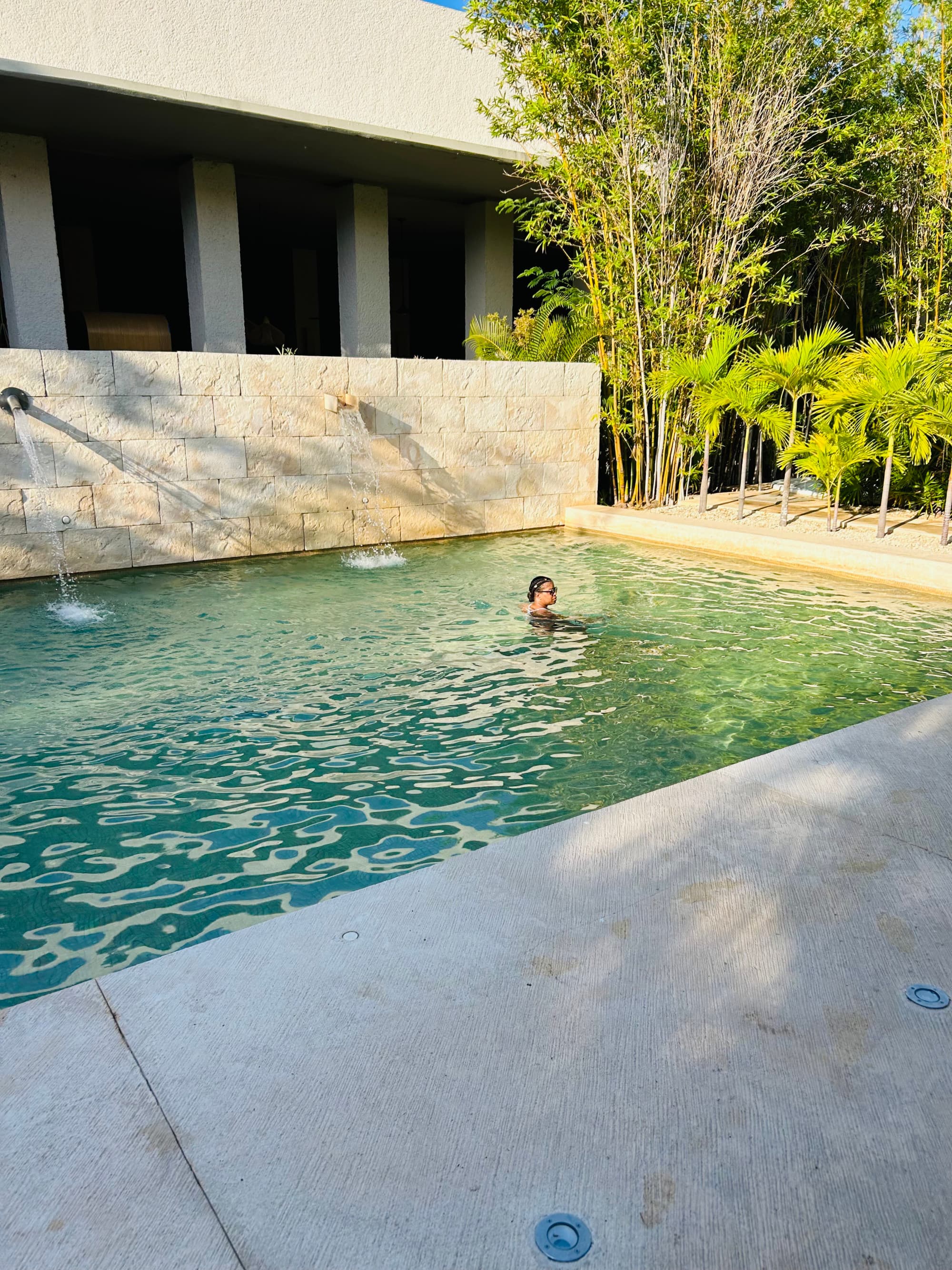 Advisor swimming in an outside pool connected to a building