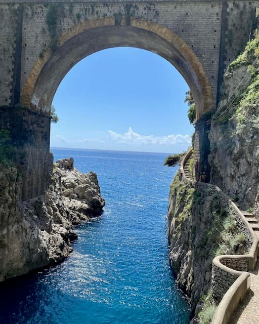 A concrete arch over blue water.