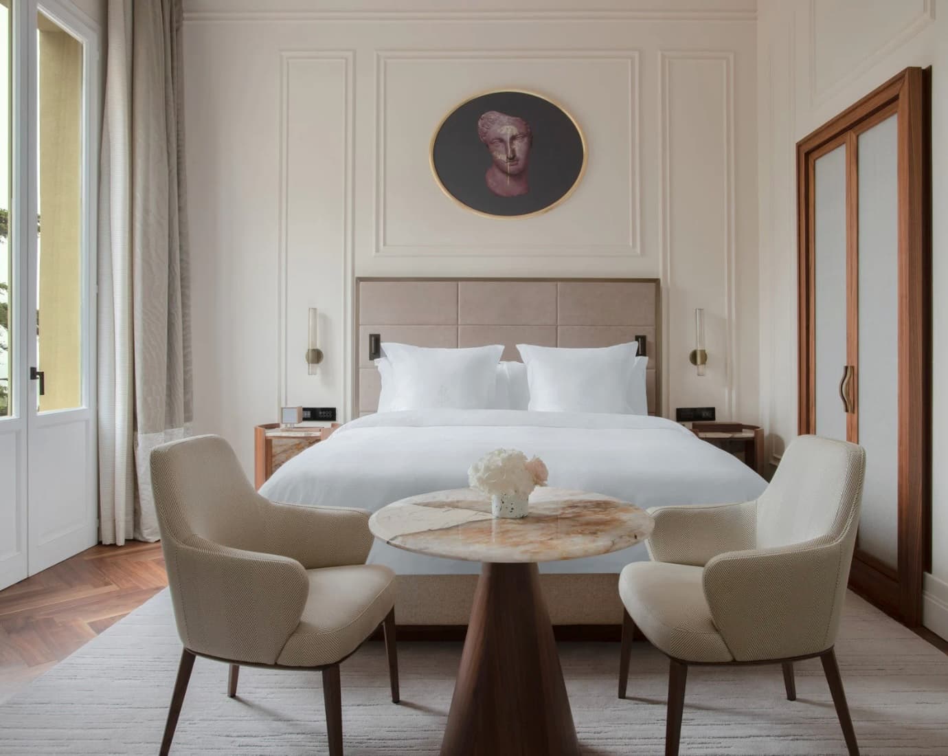 white bed in a cream-paneled room with an oval portrait over the bed