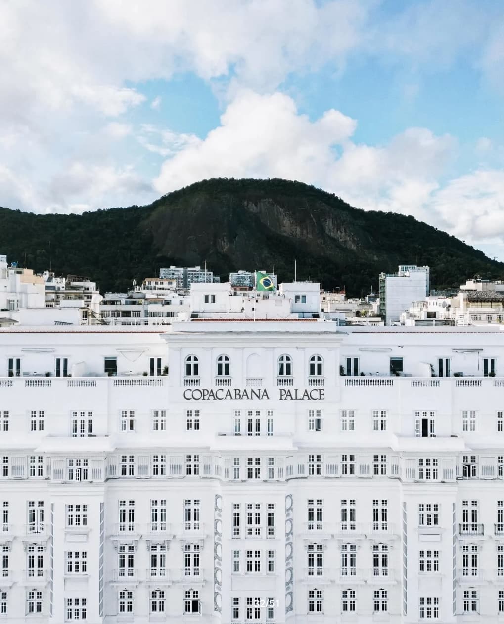 exterior of a white hotel with a mountain behind it