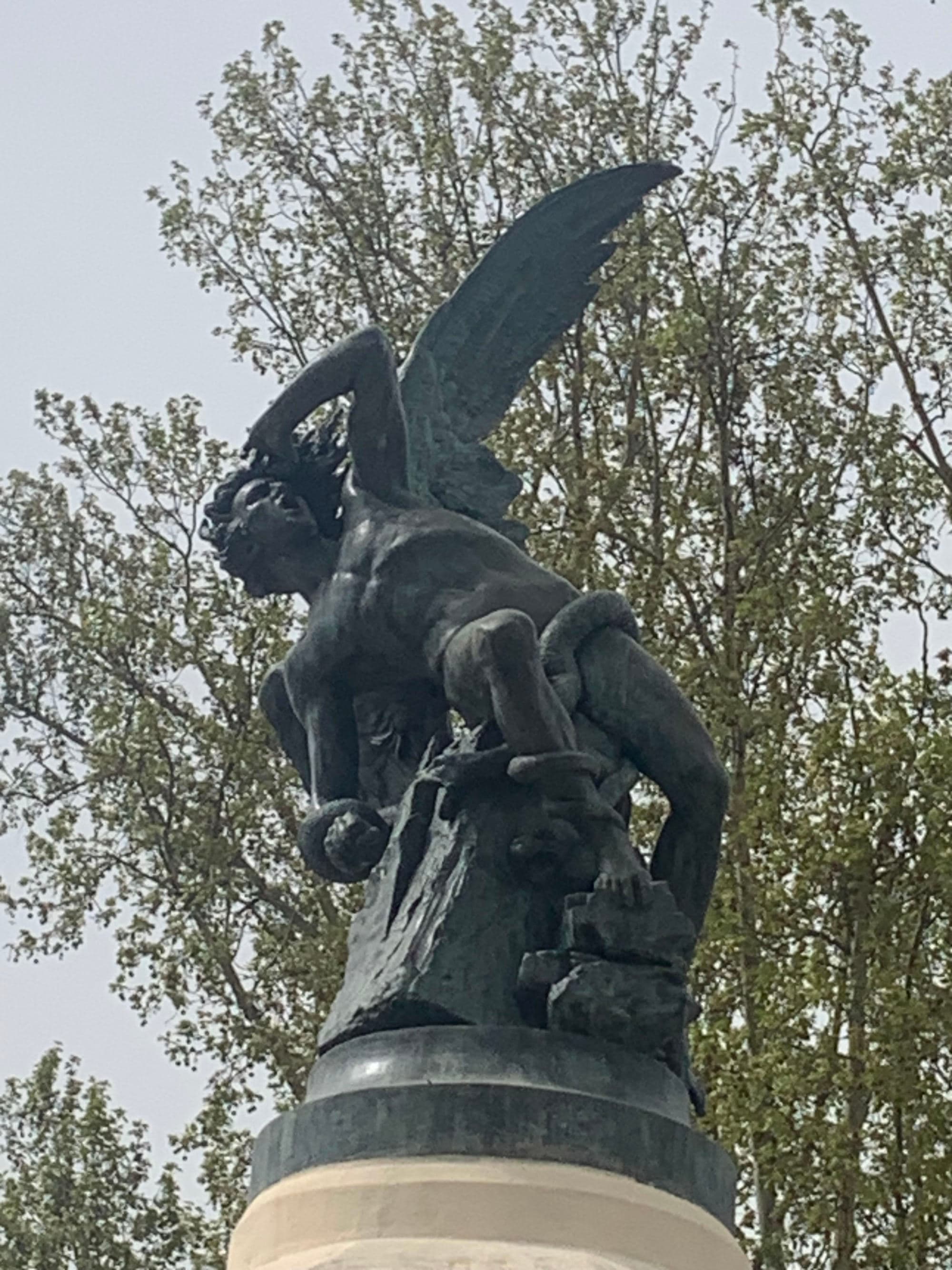 Black statue of an angel falling.