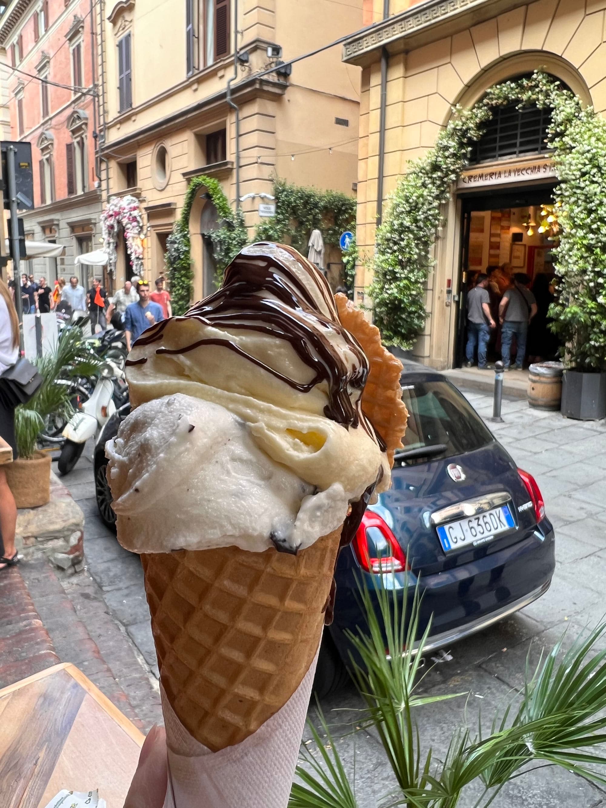 Double scooped ice cream in waffle cone on a city street.