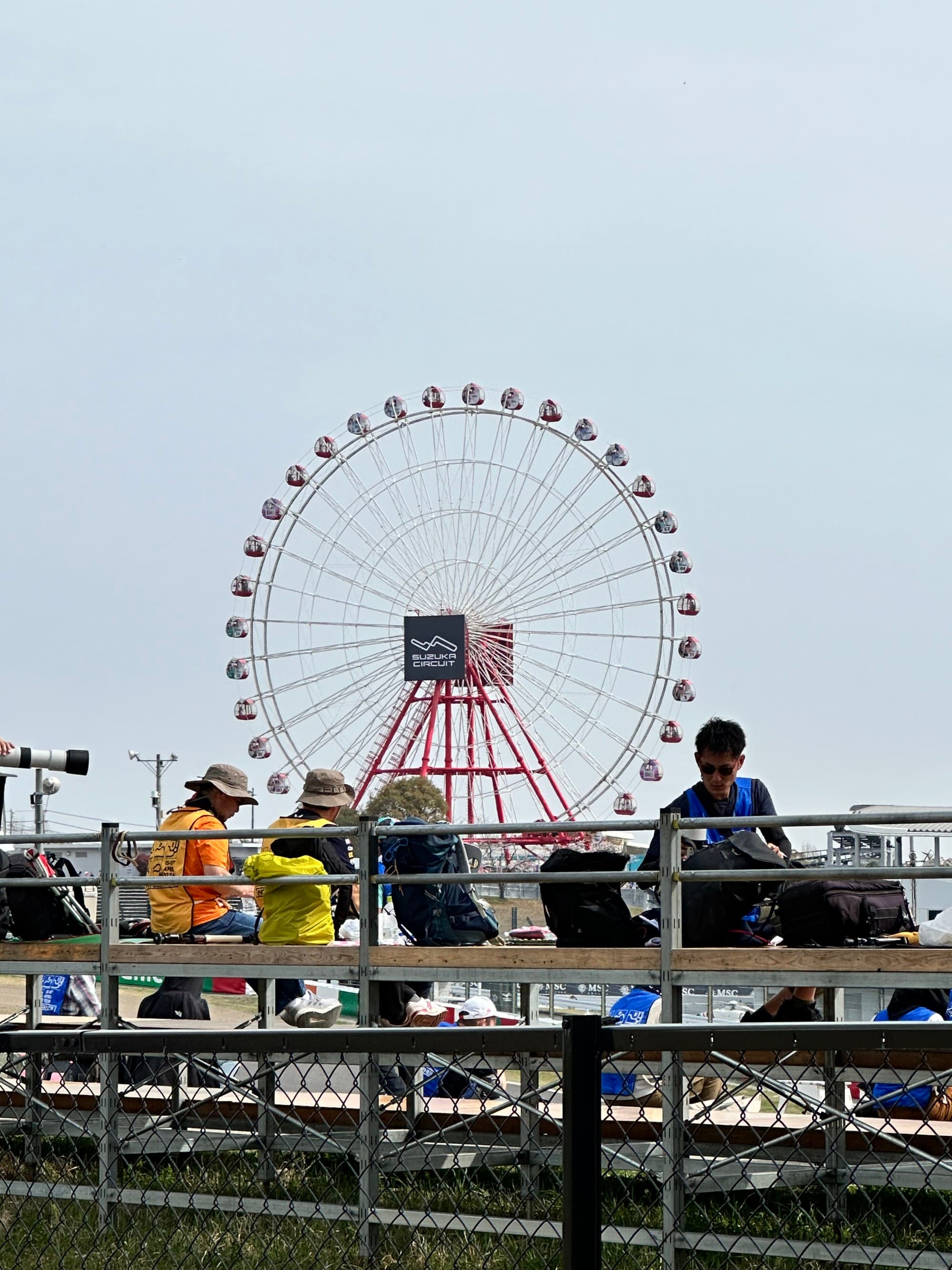 Ferris wheel with bleachers and people in the foreground.