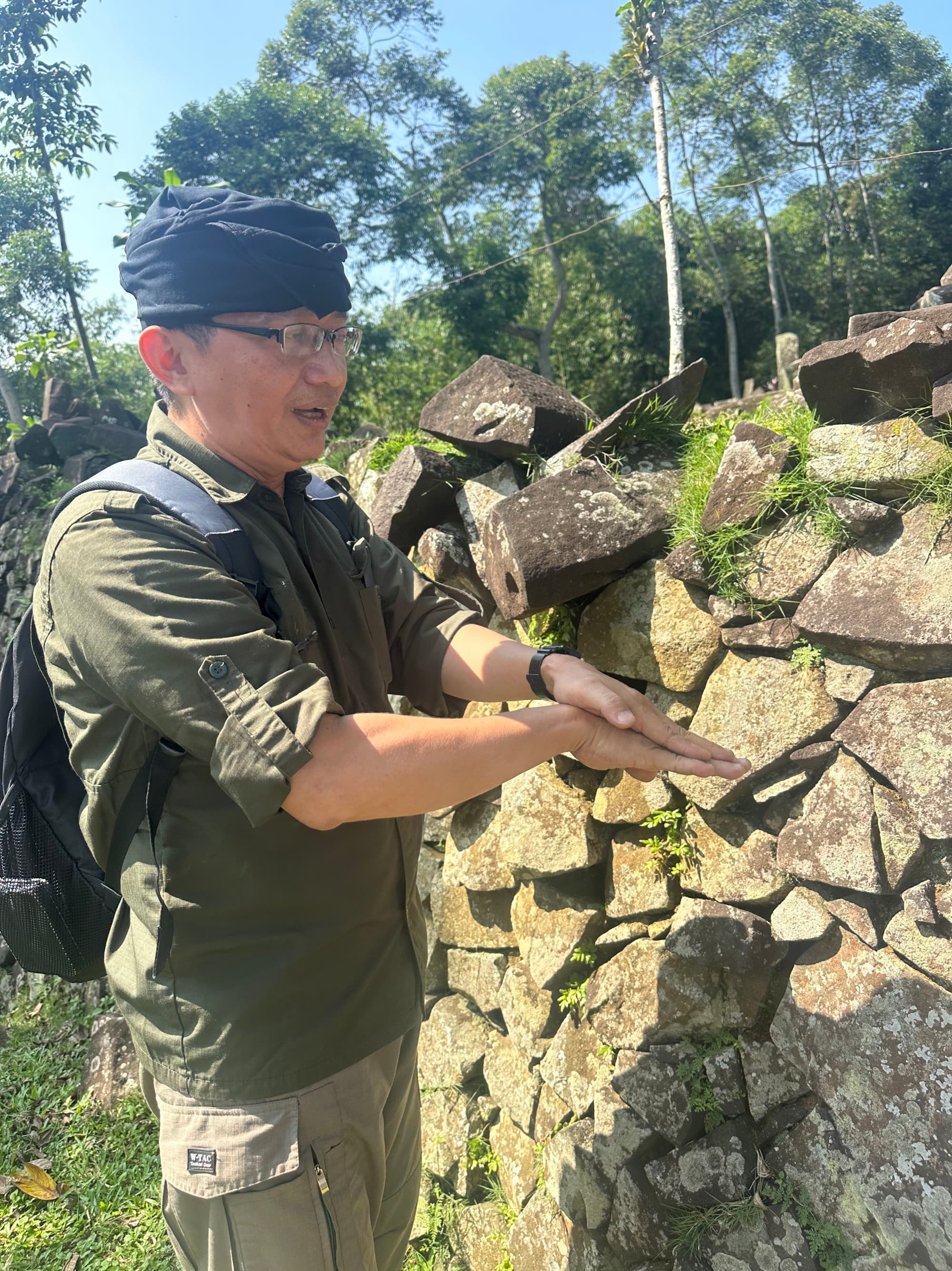 Guide speaking and gesturing with hands in front of a rock wall.