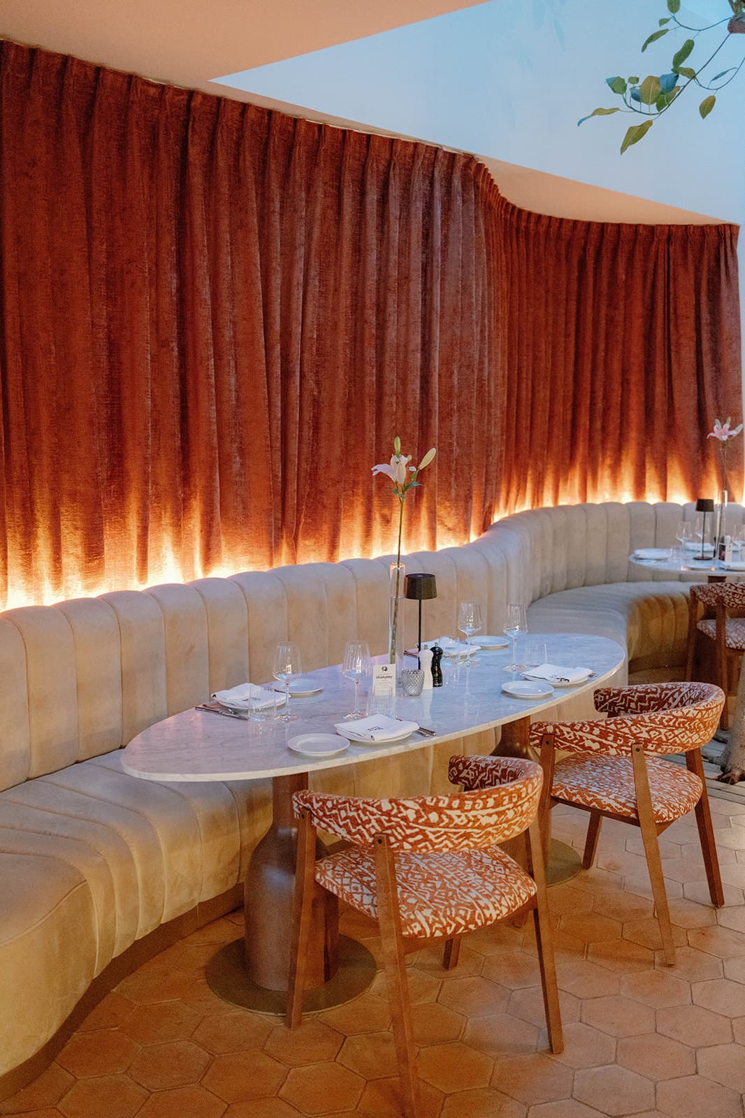 a fancy restaurant dining room with a curvy wall covered in pink velvet