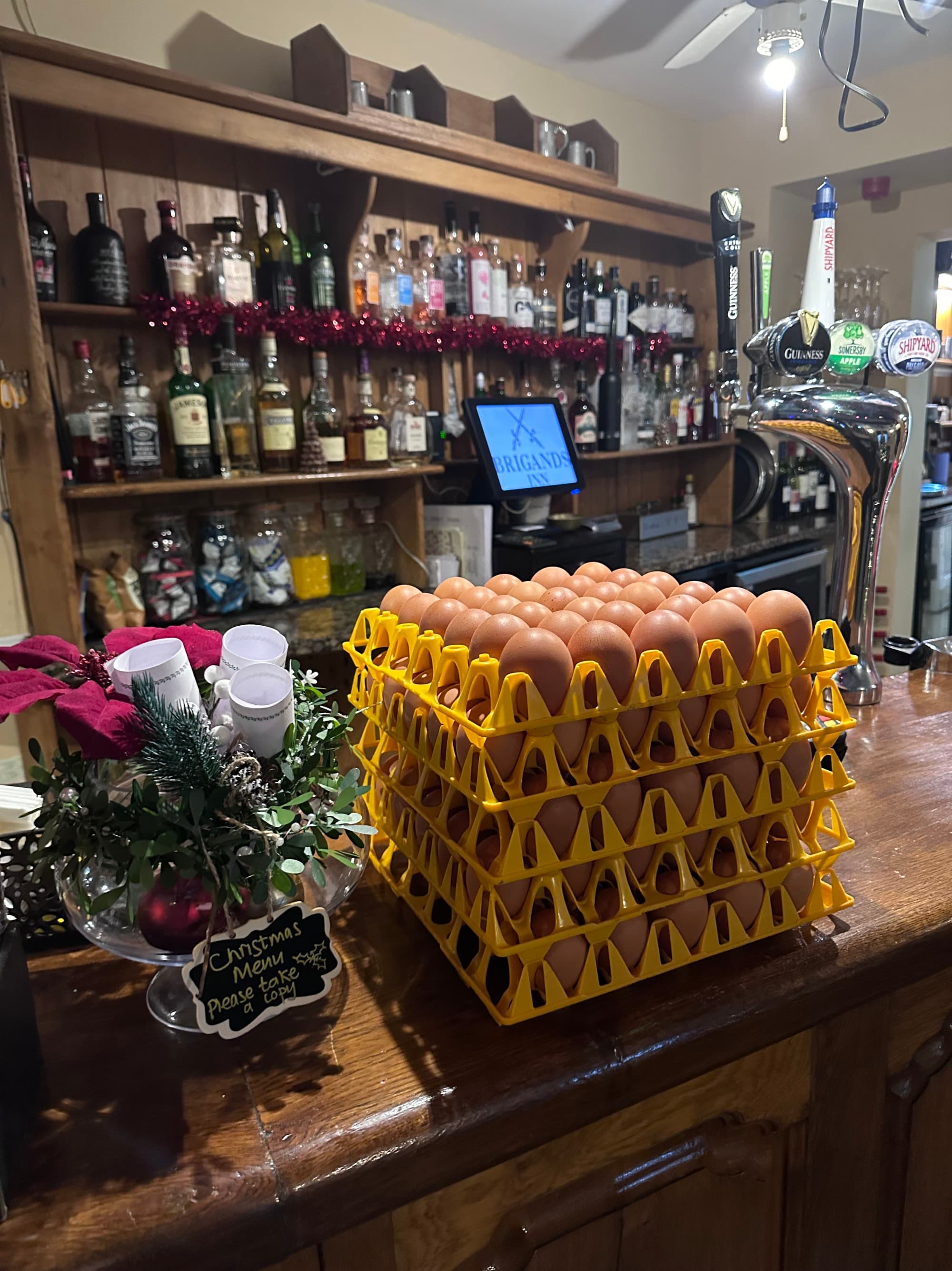View of pantry with bottles of whiskey and wine in the background and several stacked pallets of eggs.