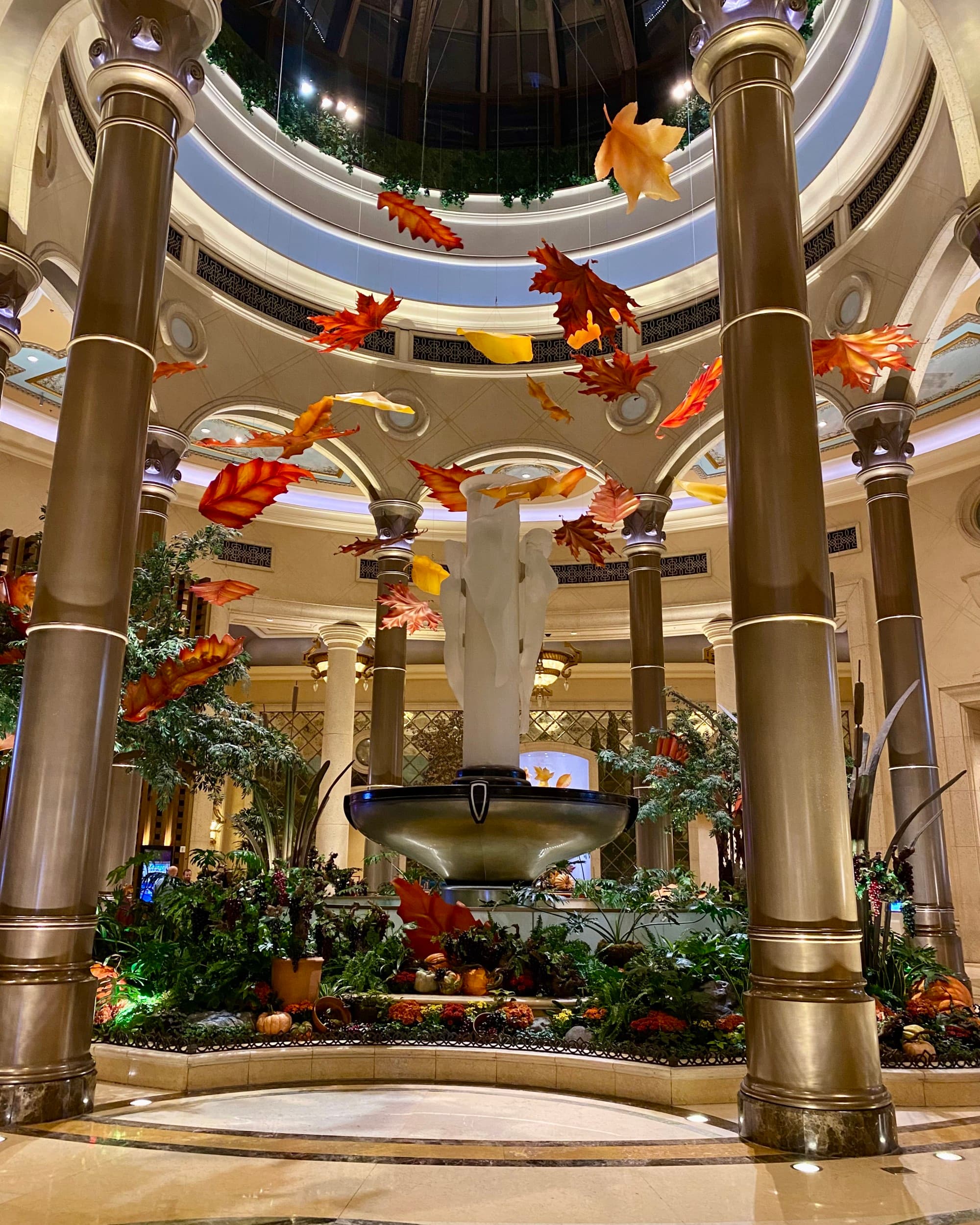 A view of a lobby of one of the 5 star hotels on Las Vegas strip with grand pillars and large hanging leaves and a central garden.