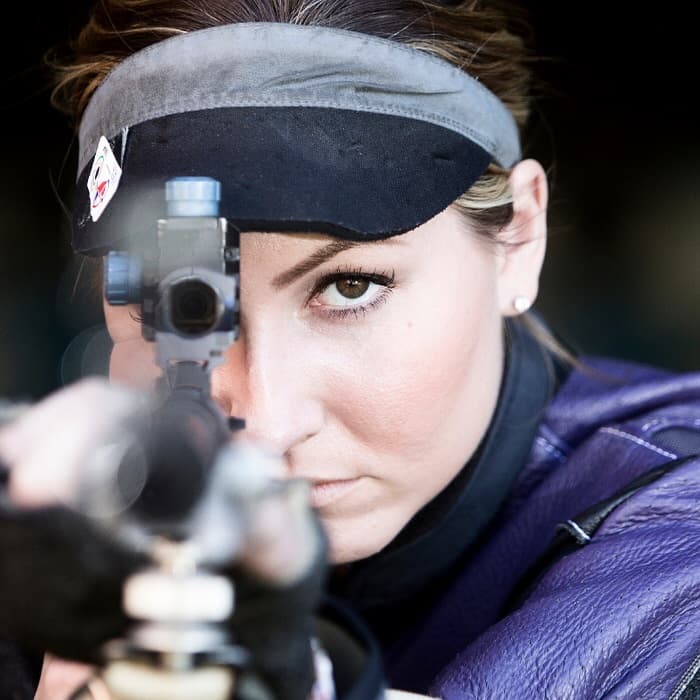close up of a woman looking through a rifle target