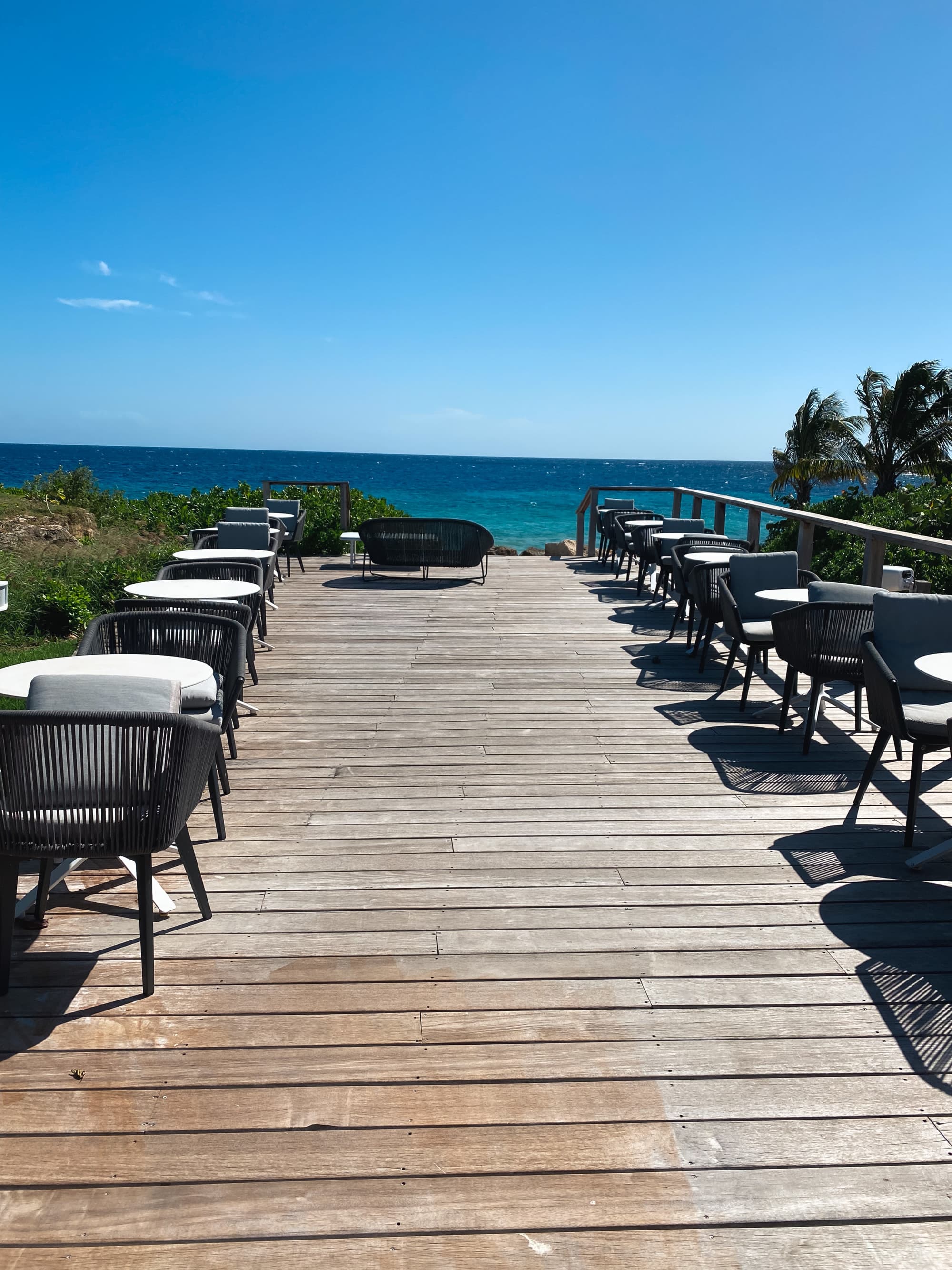 A beachside dining area on a boardwalk with a blue sky behind.