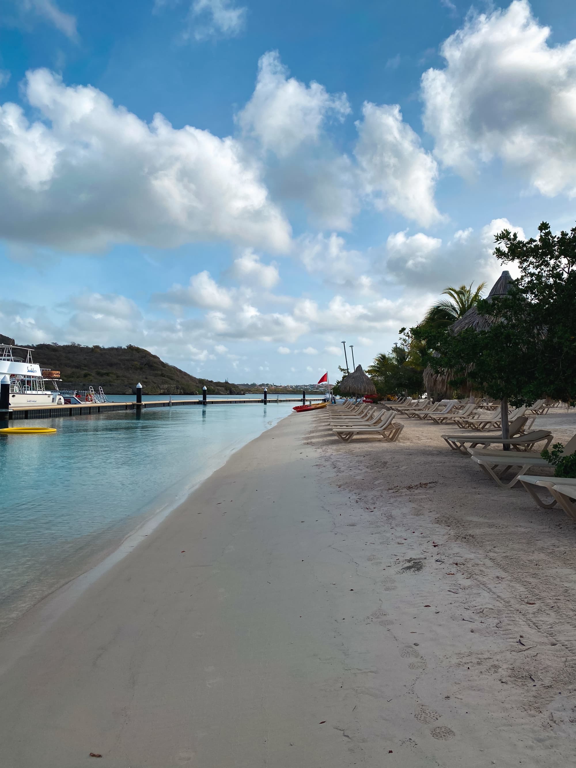 Beach along the ocean with a forest on one side and a boardwalk in the distance.