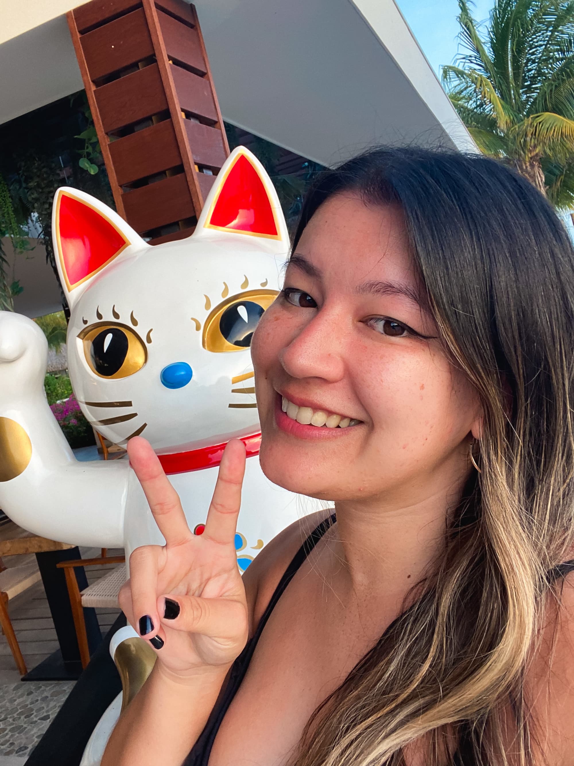 Travel advisor posing in front of a Japanese cat sculpture.