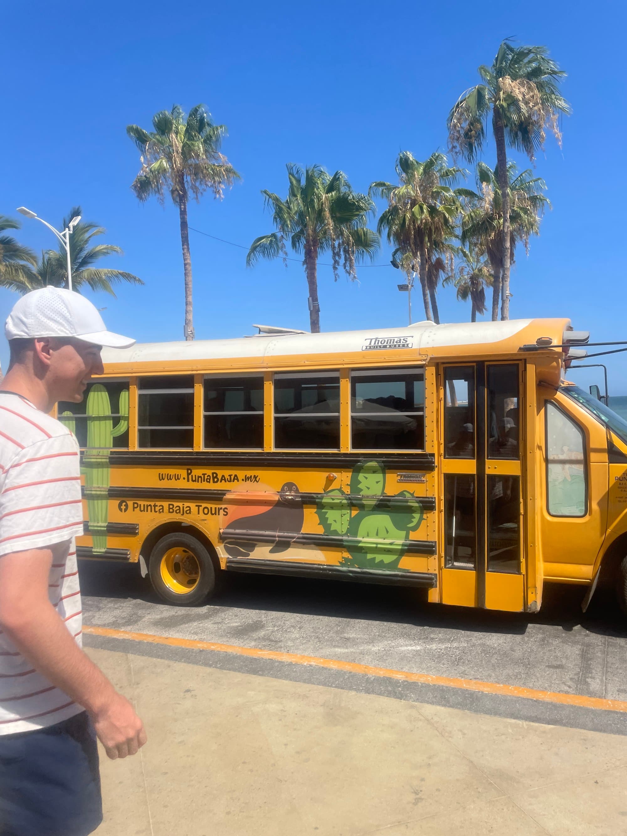 Yellow food truck with palm trees in the background.