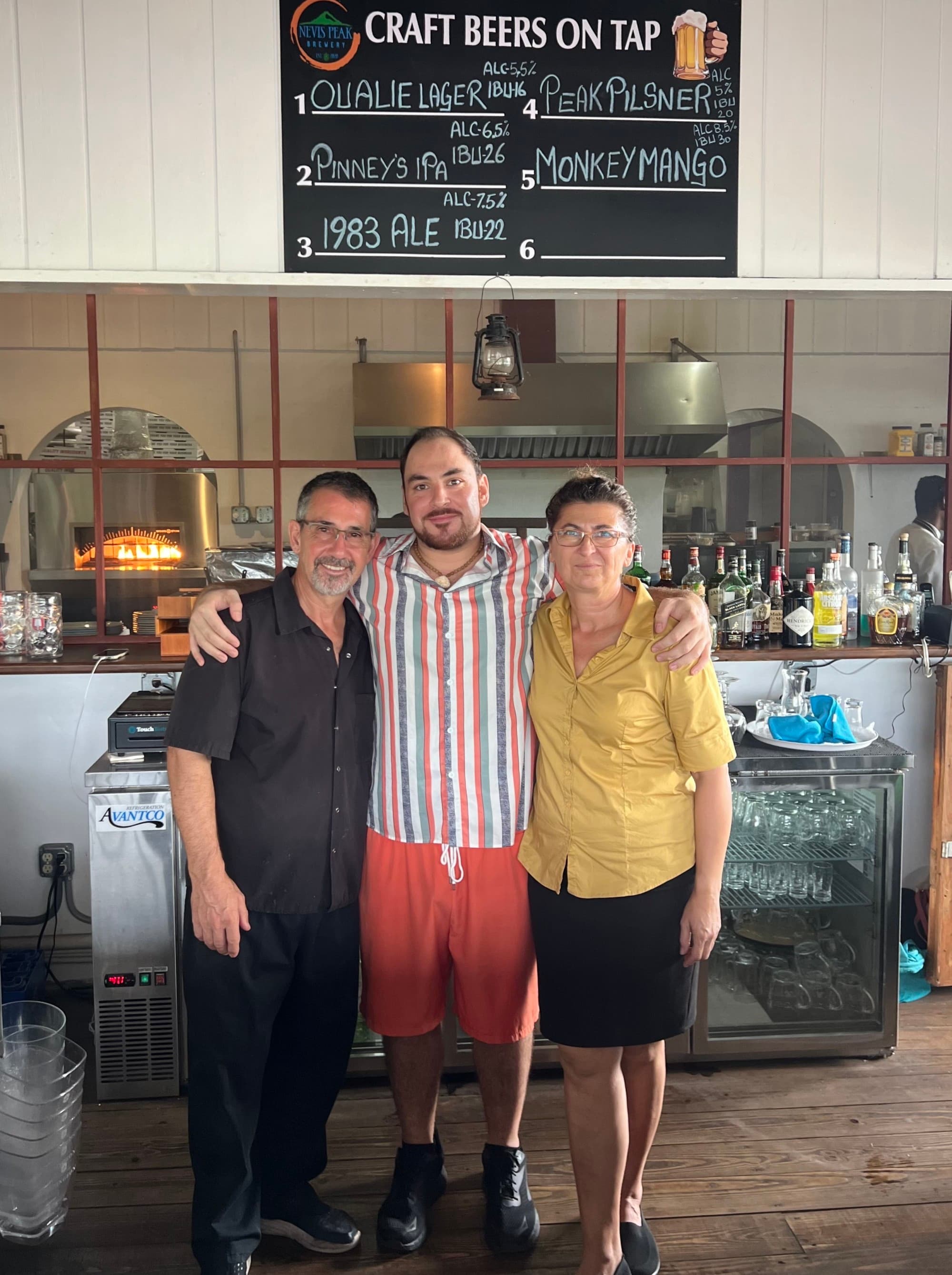 Three people stand next to each other and smile in a brewery