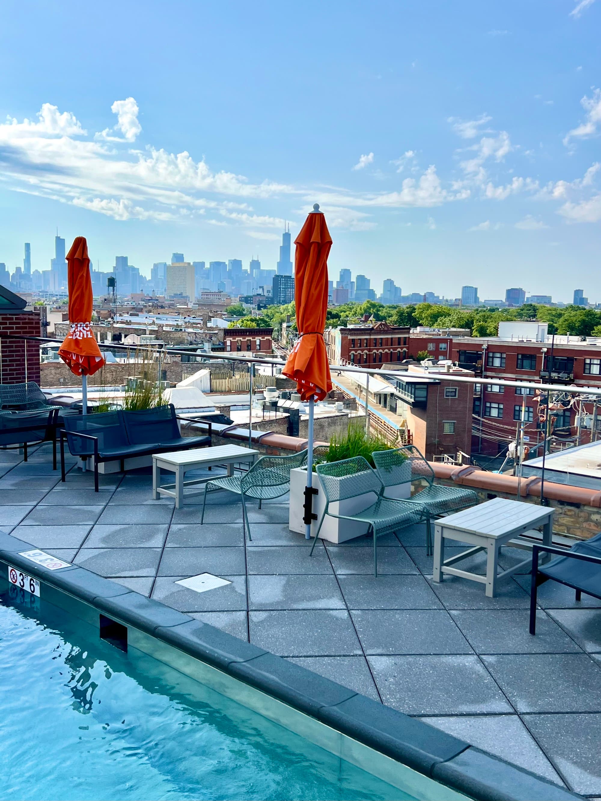 Rooftop pool with high-top tables and orange umbrellas.