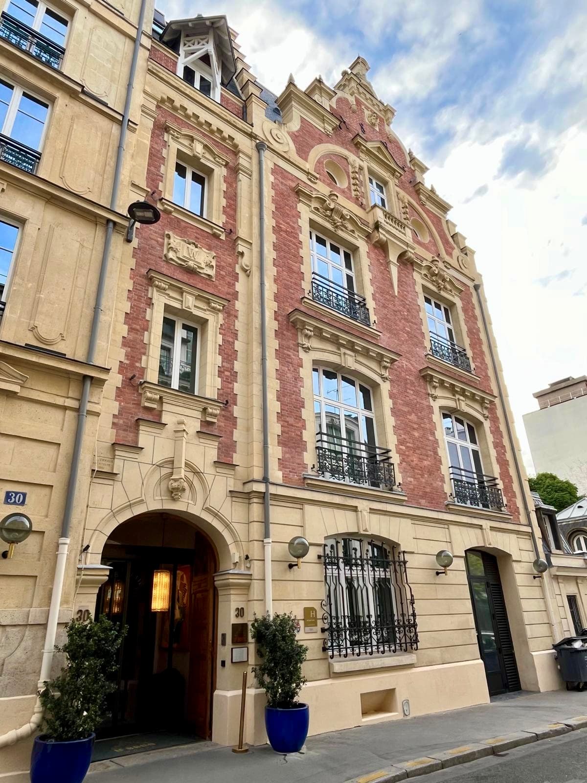 Exterior of an Art Deco hotel building in yellow and pink stone.