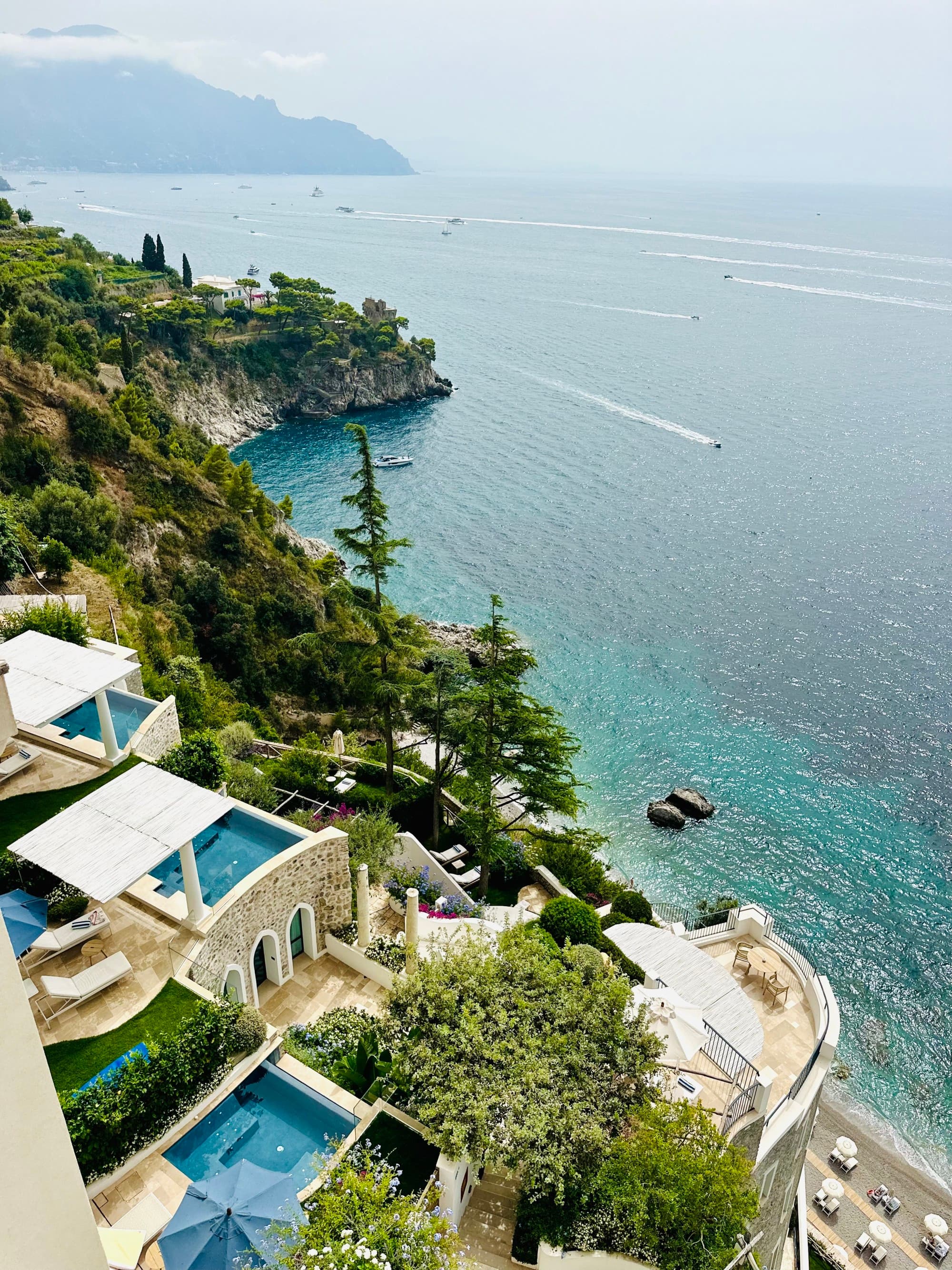 Borgo Sant'Andrea from the terrace boasts sweeping coastal views on a sunny day over crystal-clear waters.