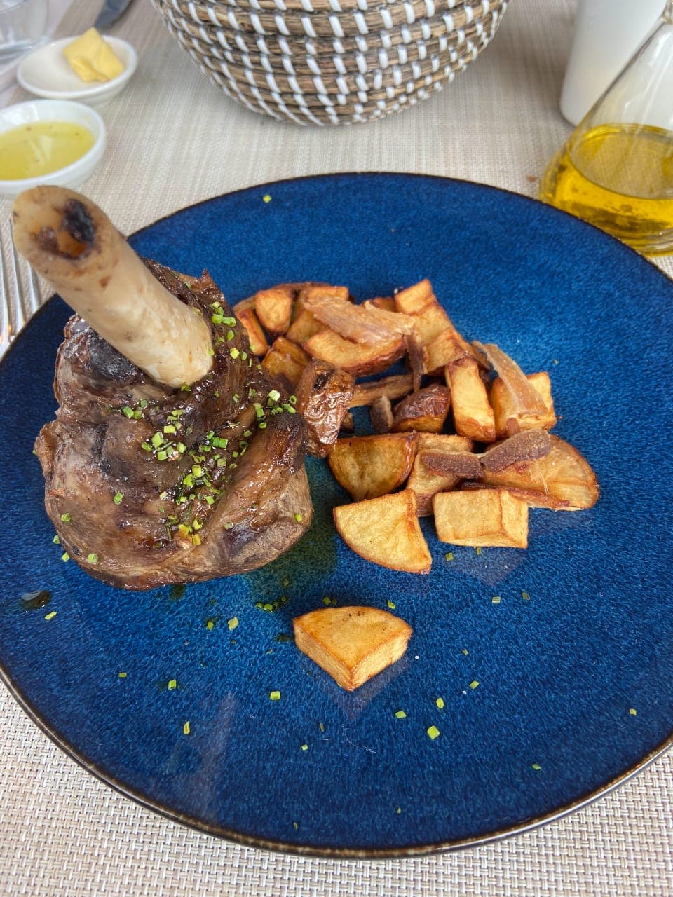 Lamp chop and potatoes on a blue plate.