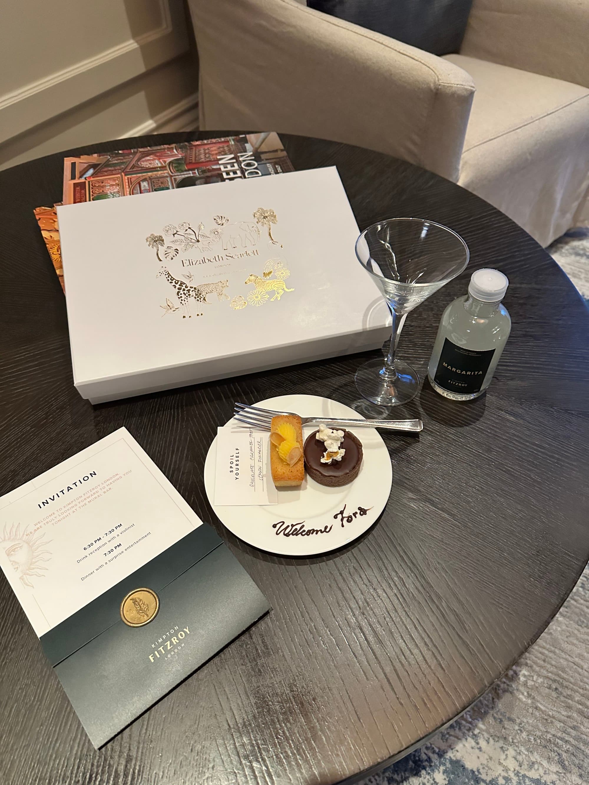 Two pastries on a white plate with a martini glass on a table.