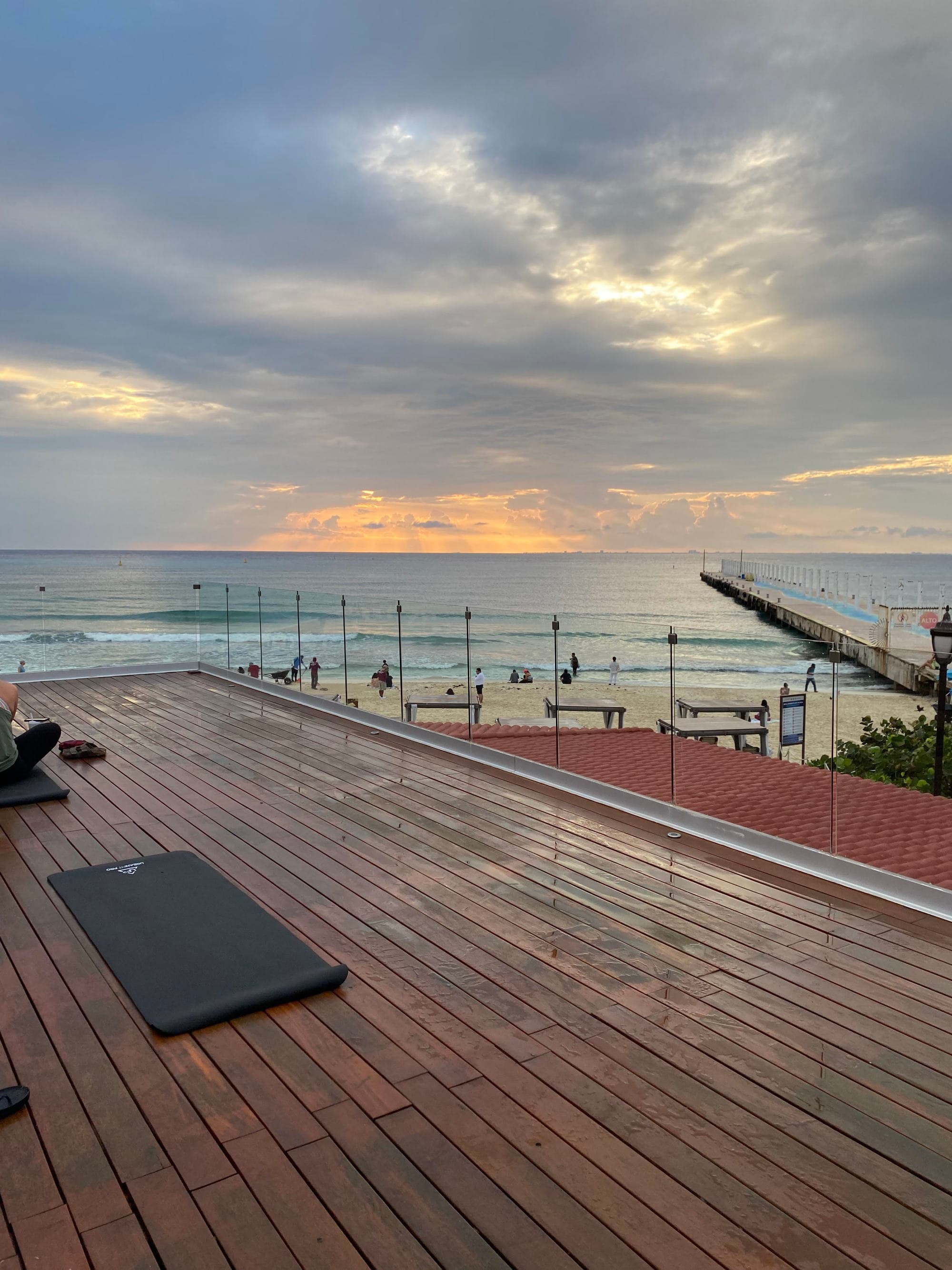 An outdoor wooden deck overlooking the ocean during a sunrise