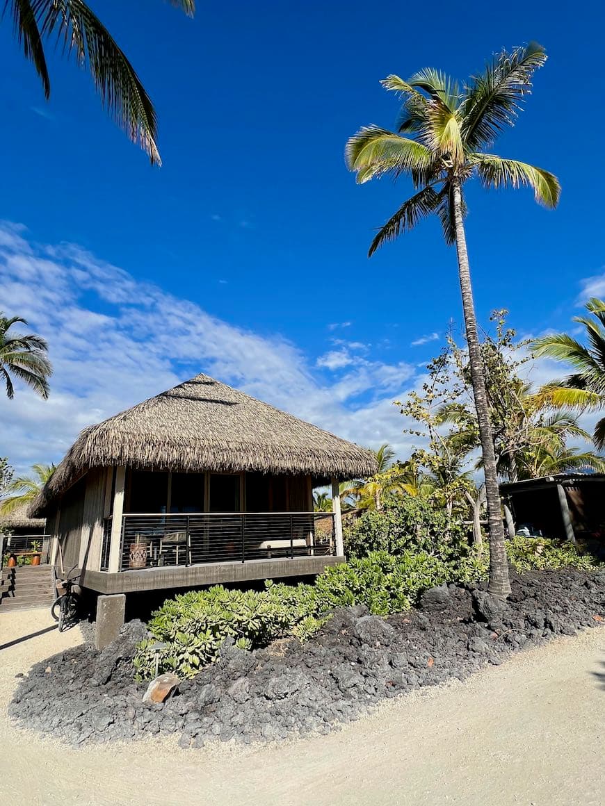 A beach hut with a straw roof in the sand during the daytime