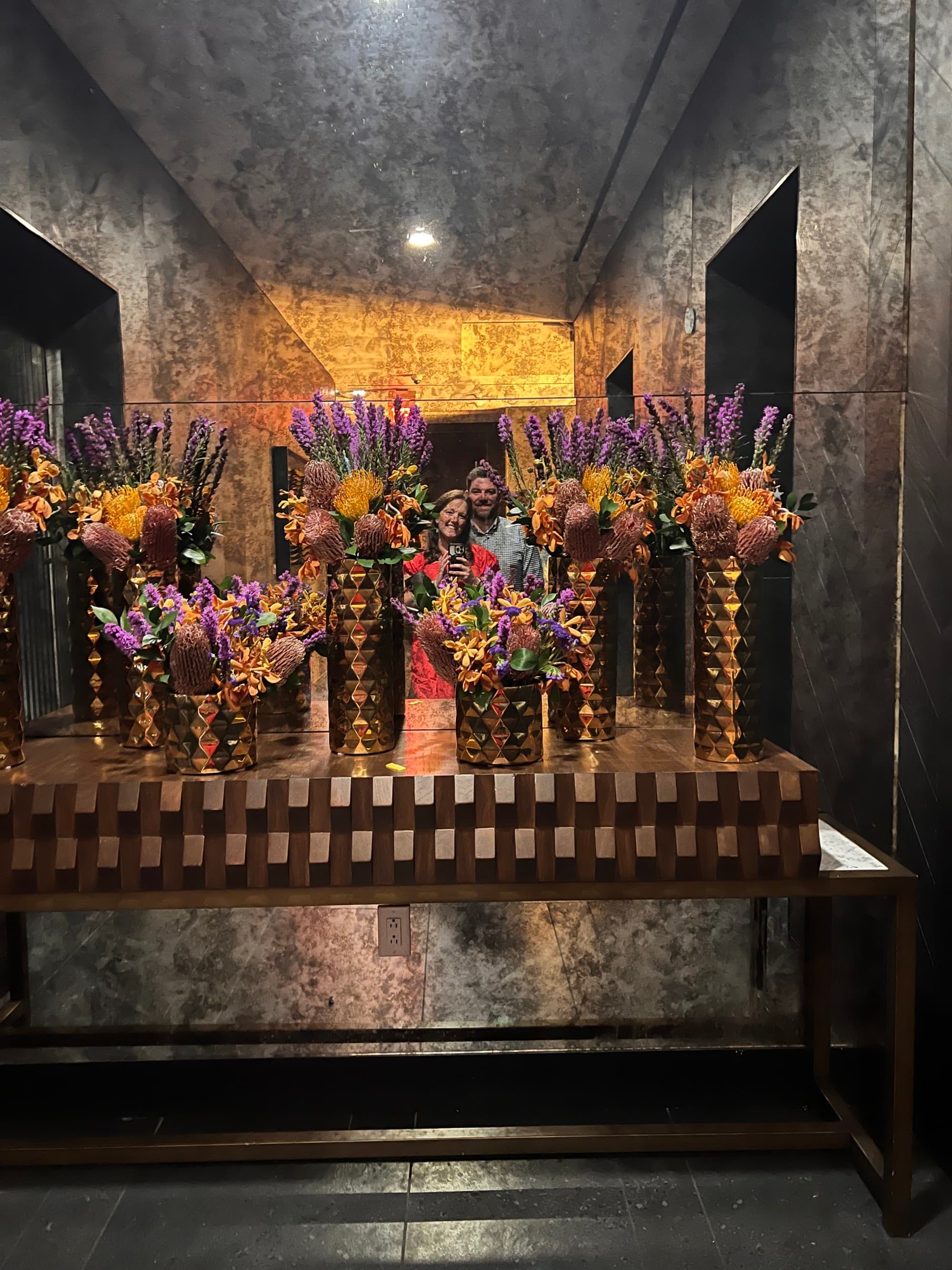 Asymmetrical vases of flowers aligned on a self