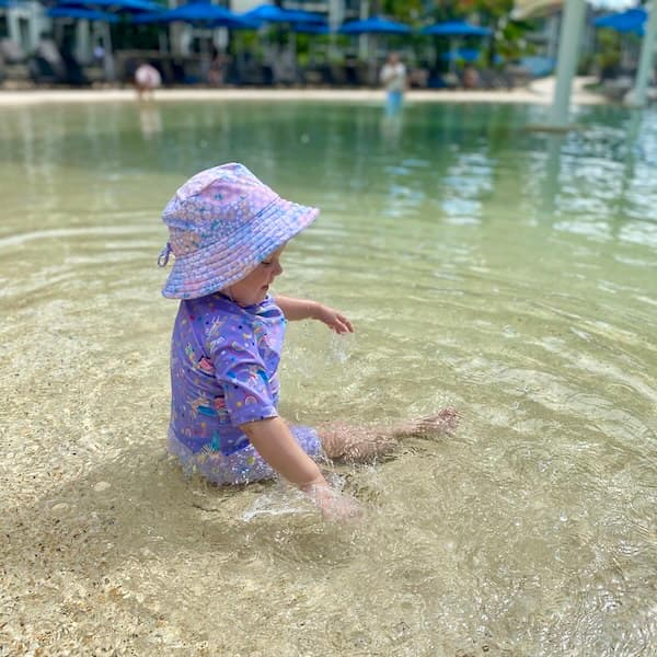 Toddler splashing in a shallow pool.