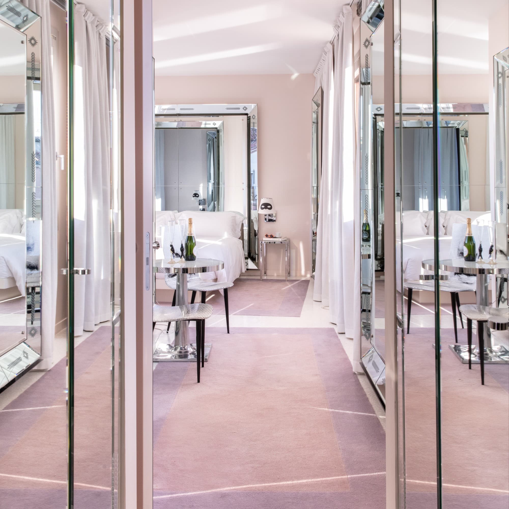 a mirrored hallway leading into a plush hotel room
