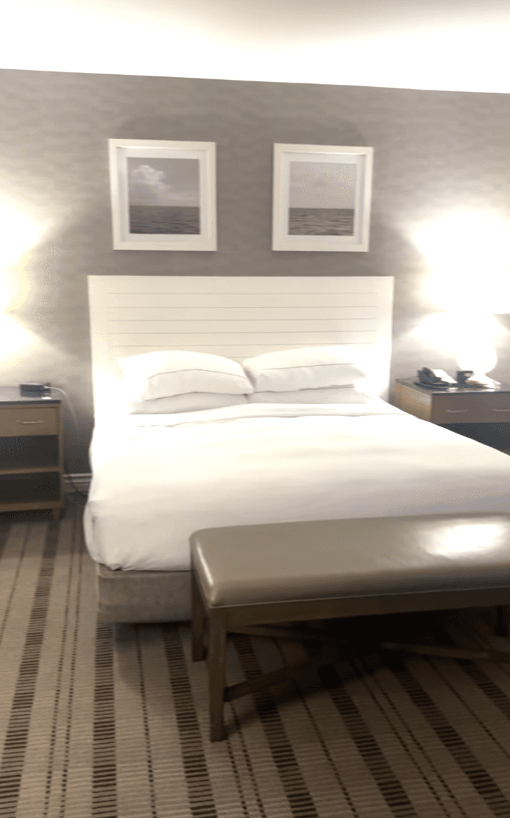 A bedroom suit with a white bed in the middle of the room