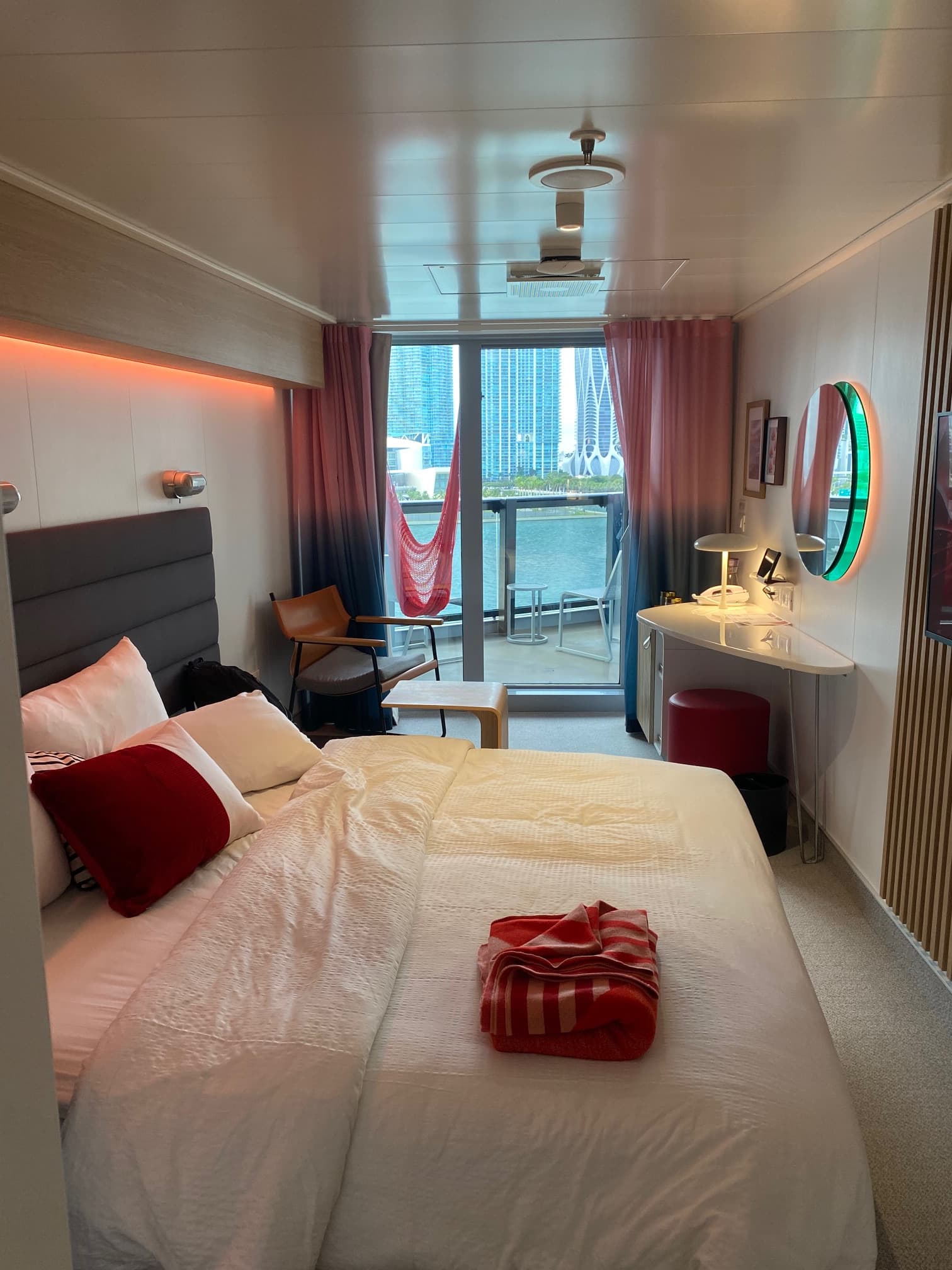 Virgin Voyages cruise bedroom features a bed and vanity with a large window.