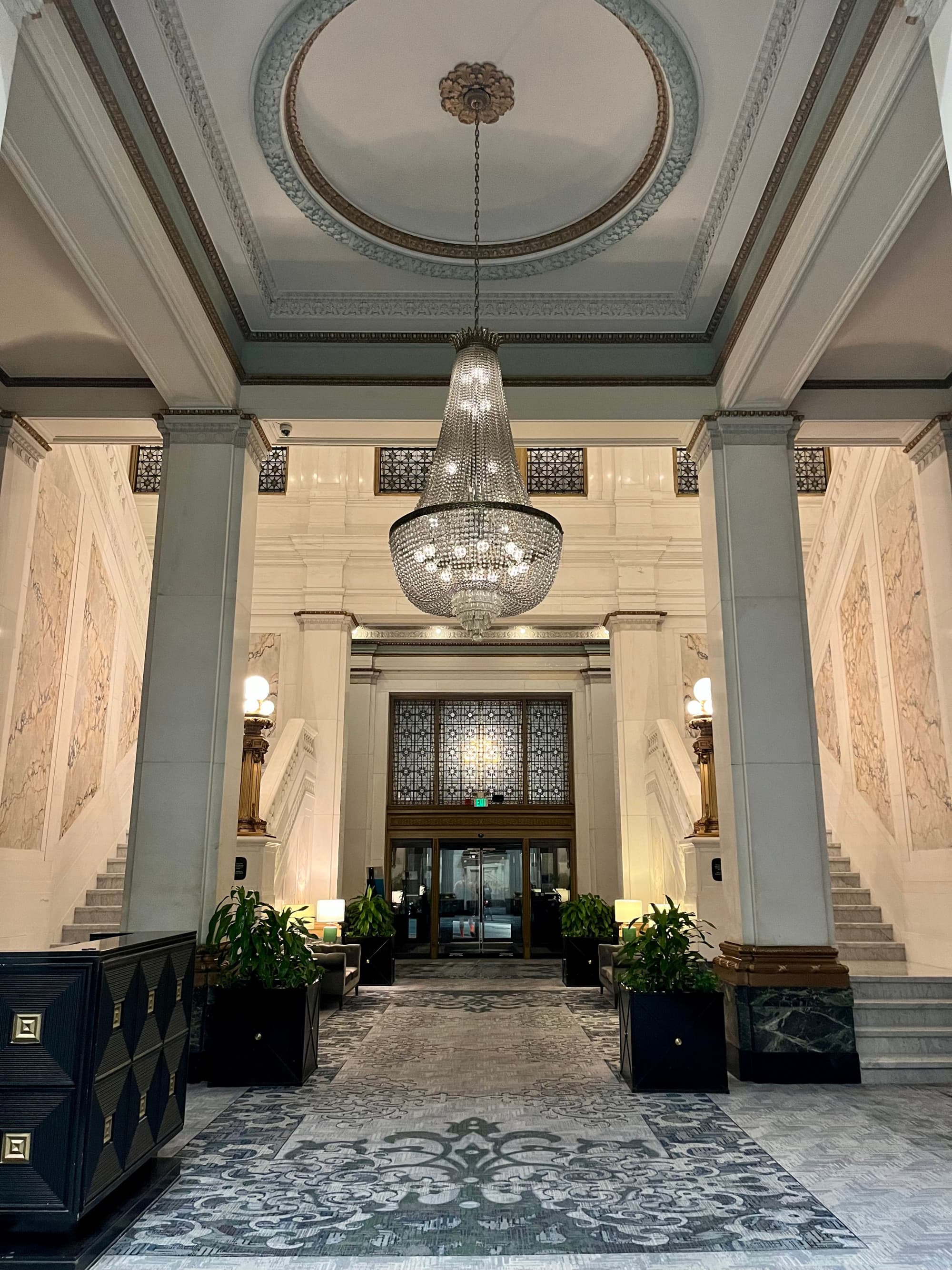 Hotel interior with a patterned tile floor and a crystal chandelier.