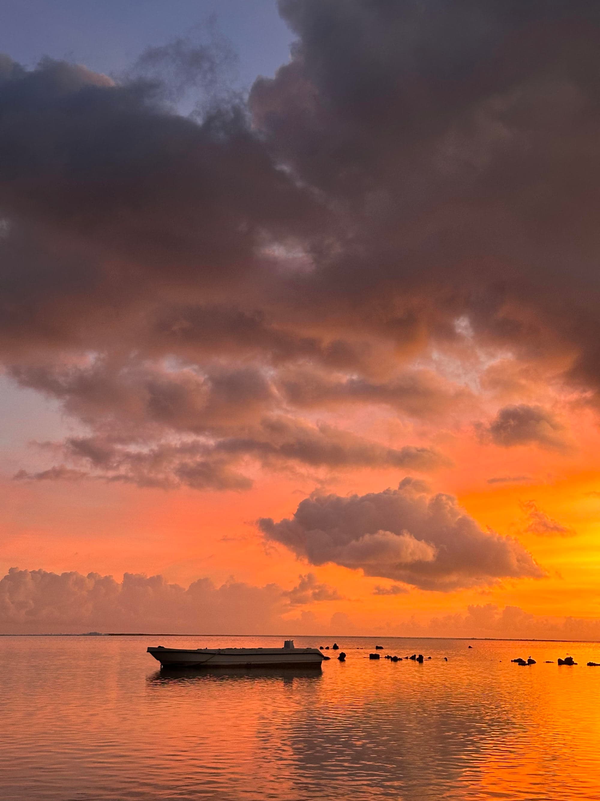 Boats on the water underneath a sunset.
