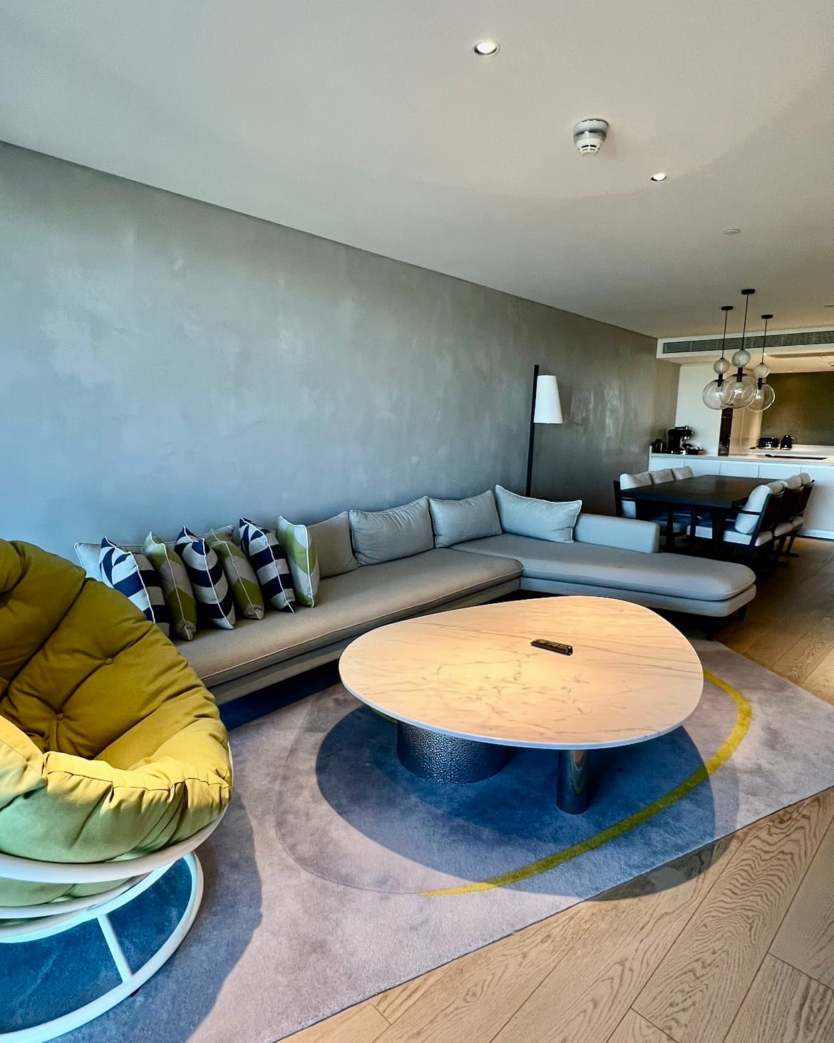 A living room area with a round table in front of a grey L-shaped sofa