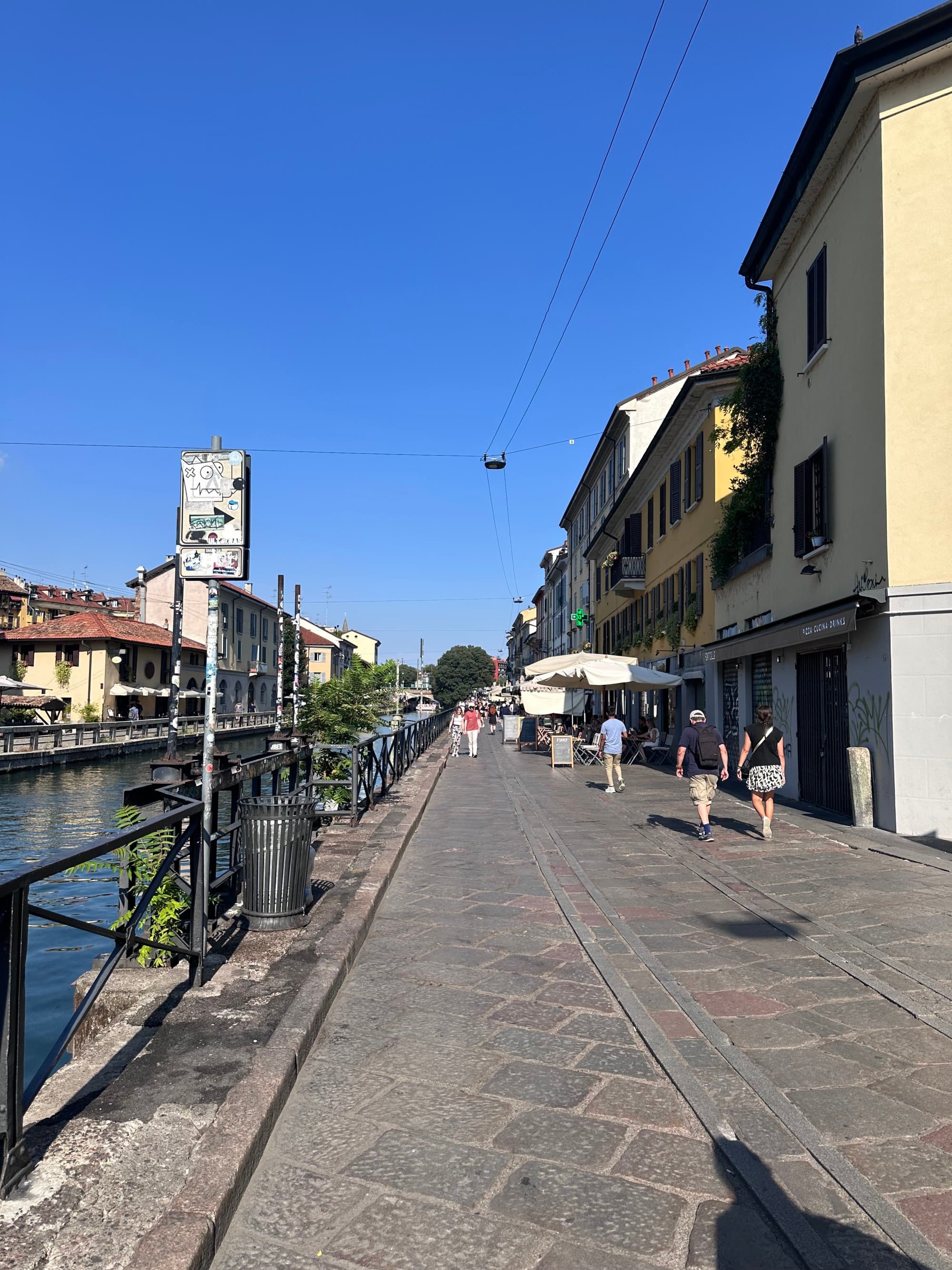 A narrow city street paved with flagstones and lined with yellow buildings.