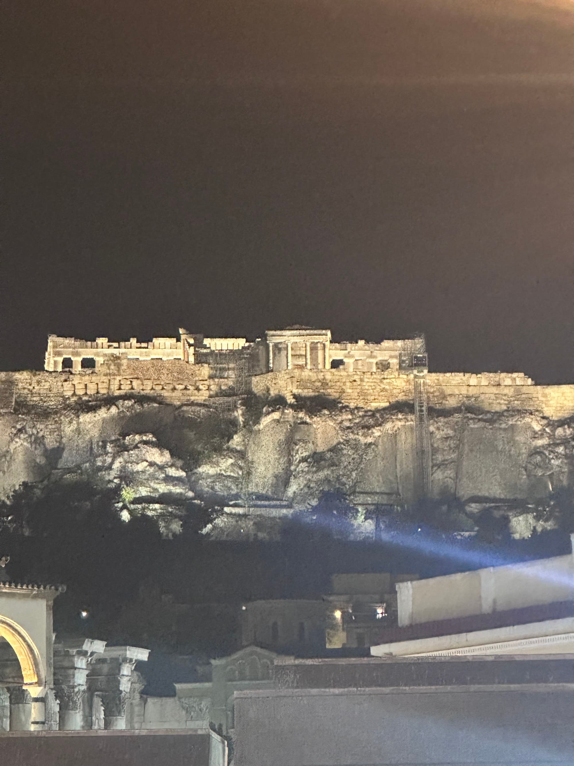 A nighttime view of ancient ruins on top of a hill.