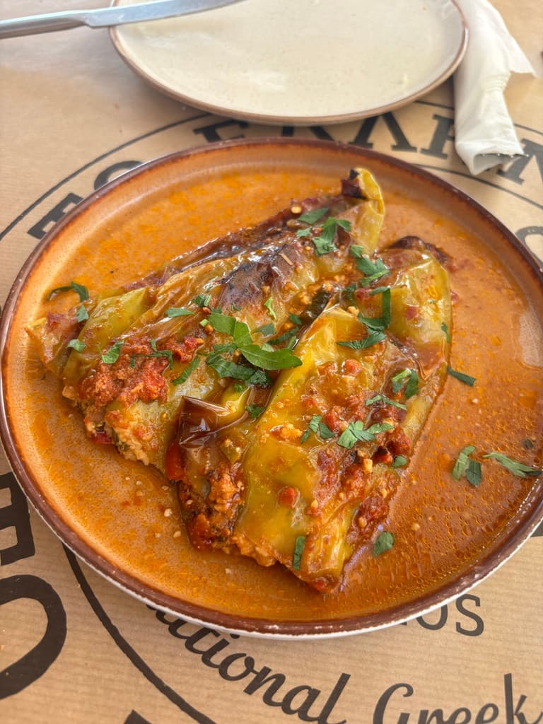 Meat in a thick orange sauce in a stoneware bowl.