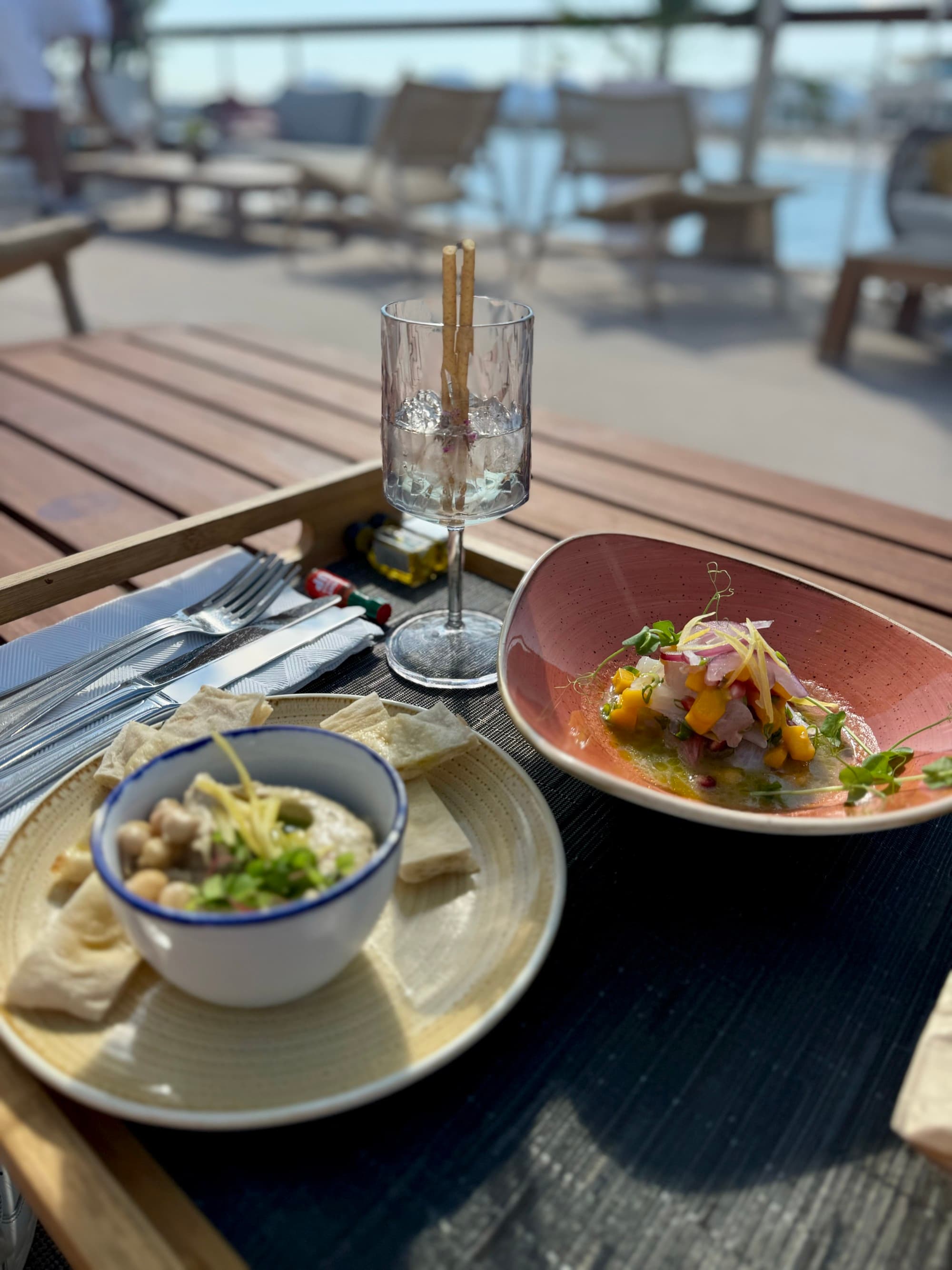 Table set with delectable snacks with a poolside view on a sunny day.