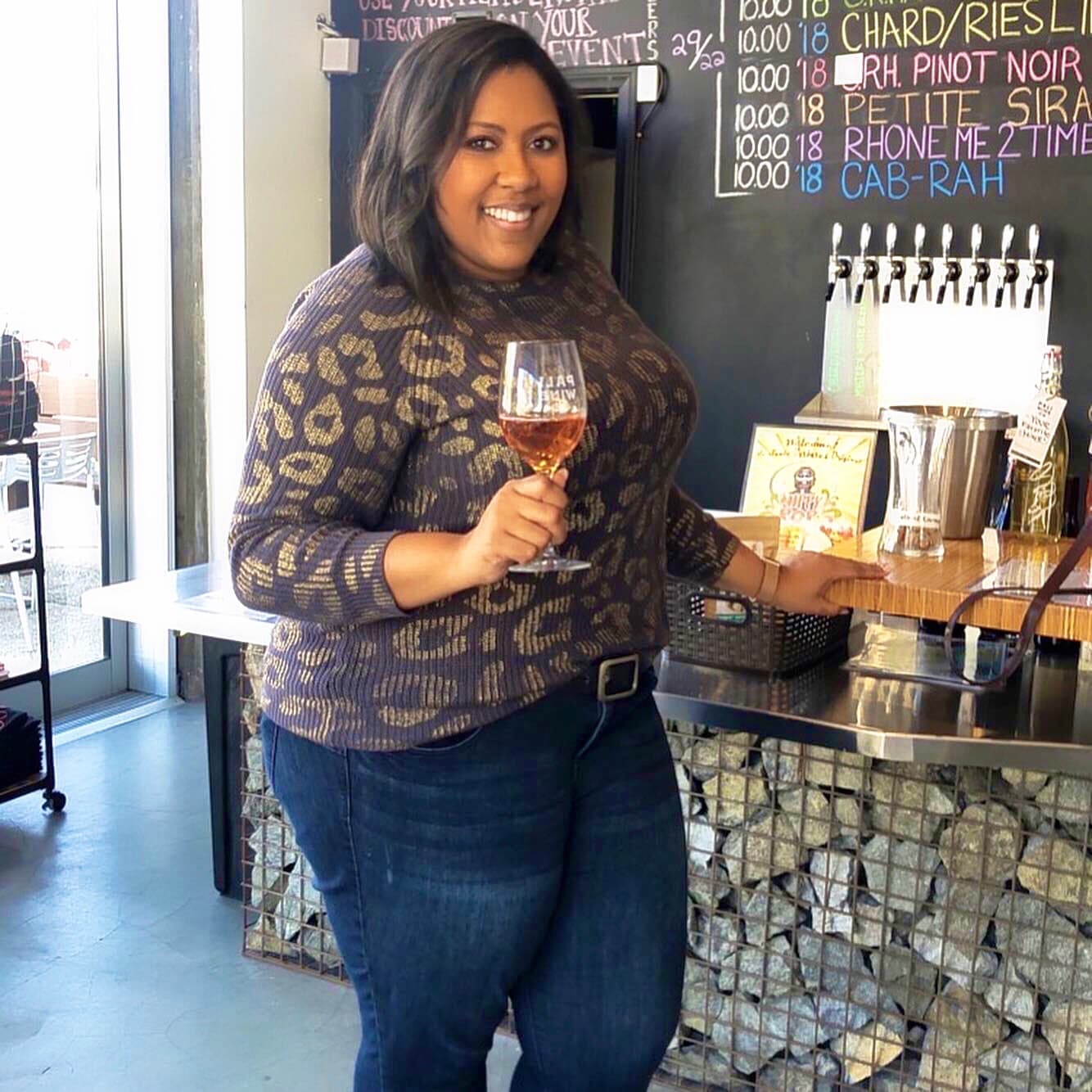 Advisor smiling and holding a glass of wine inside a winery during the day