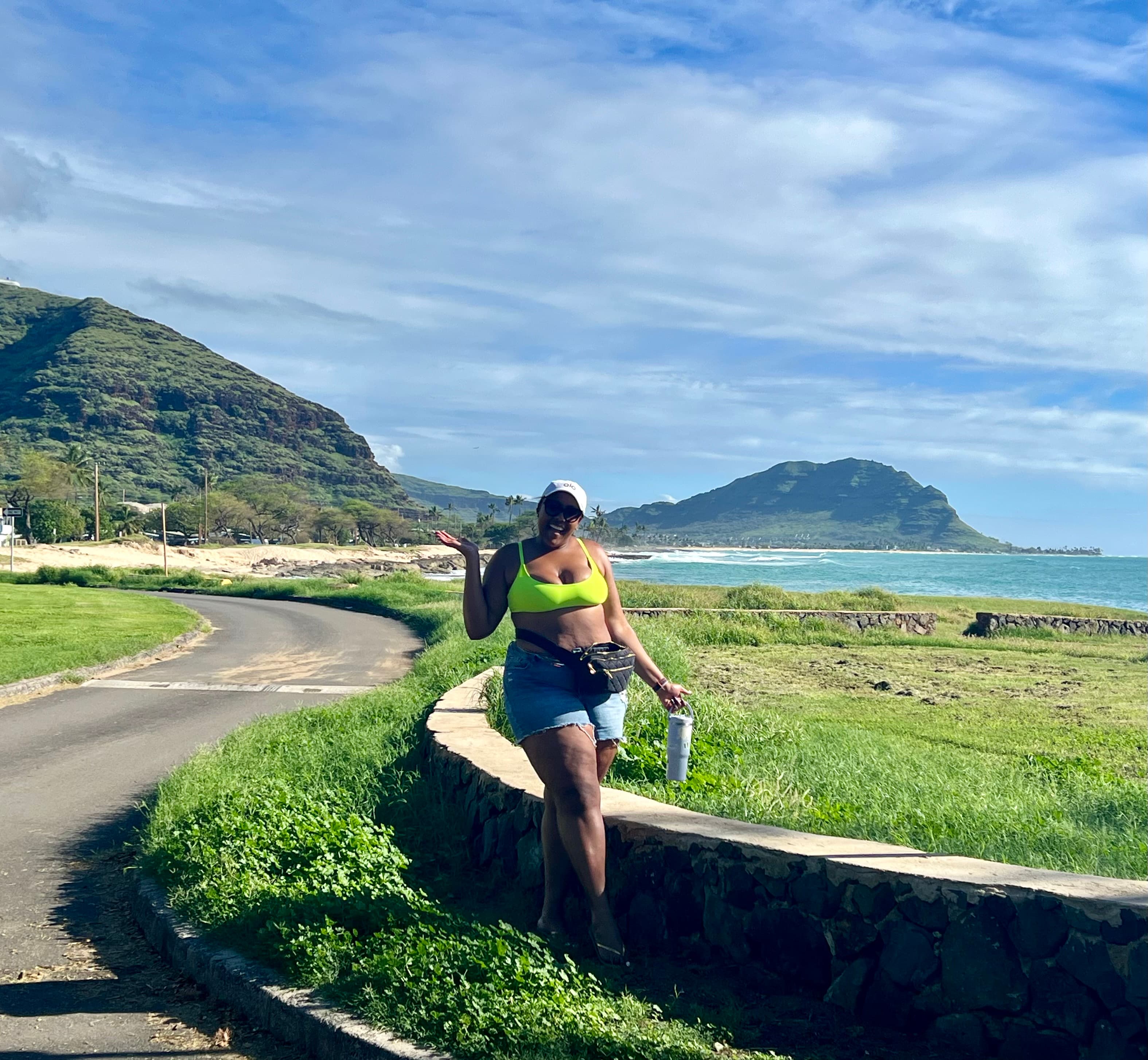 Advisor walking on a remote road by the sea with green cliffs behind her