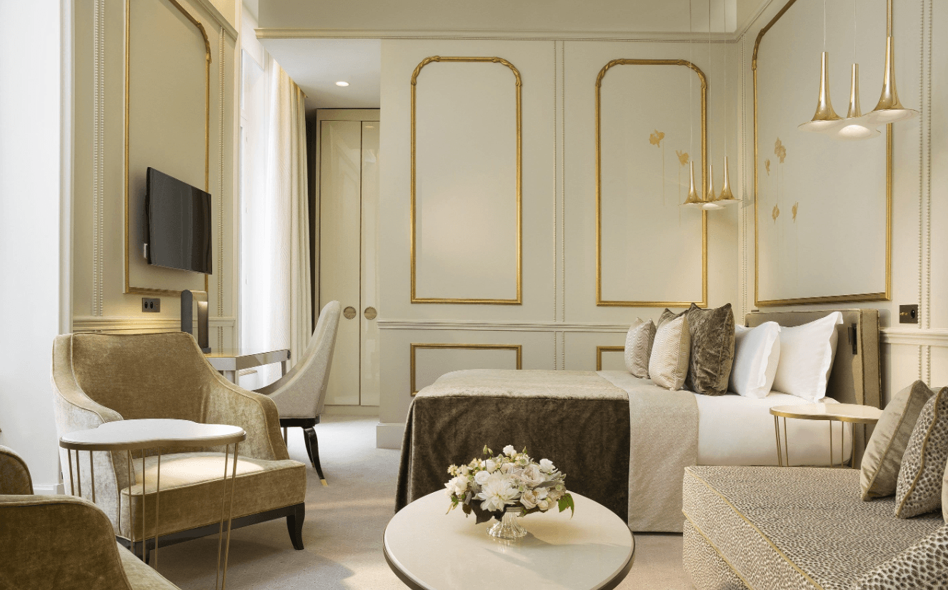 An elegant hotel room at Le Narcisse Blanc Hotel & Spa with cream and gold furnishings and fixtures.