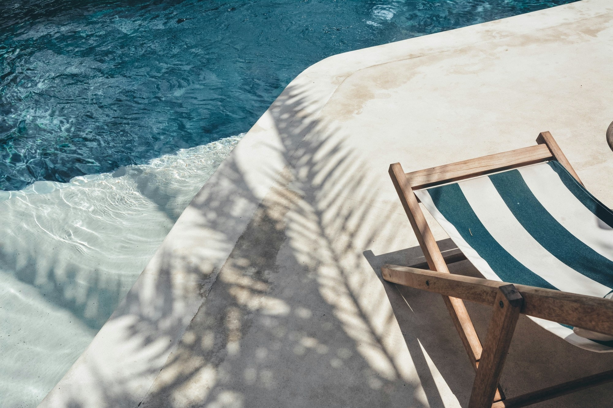 a striped cloth lounge chair near the side of a pool