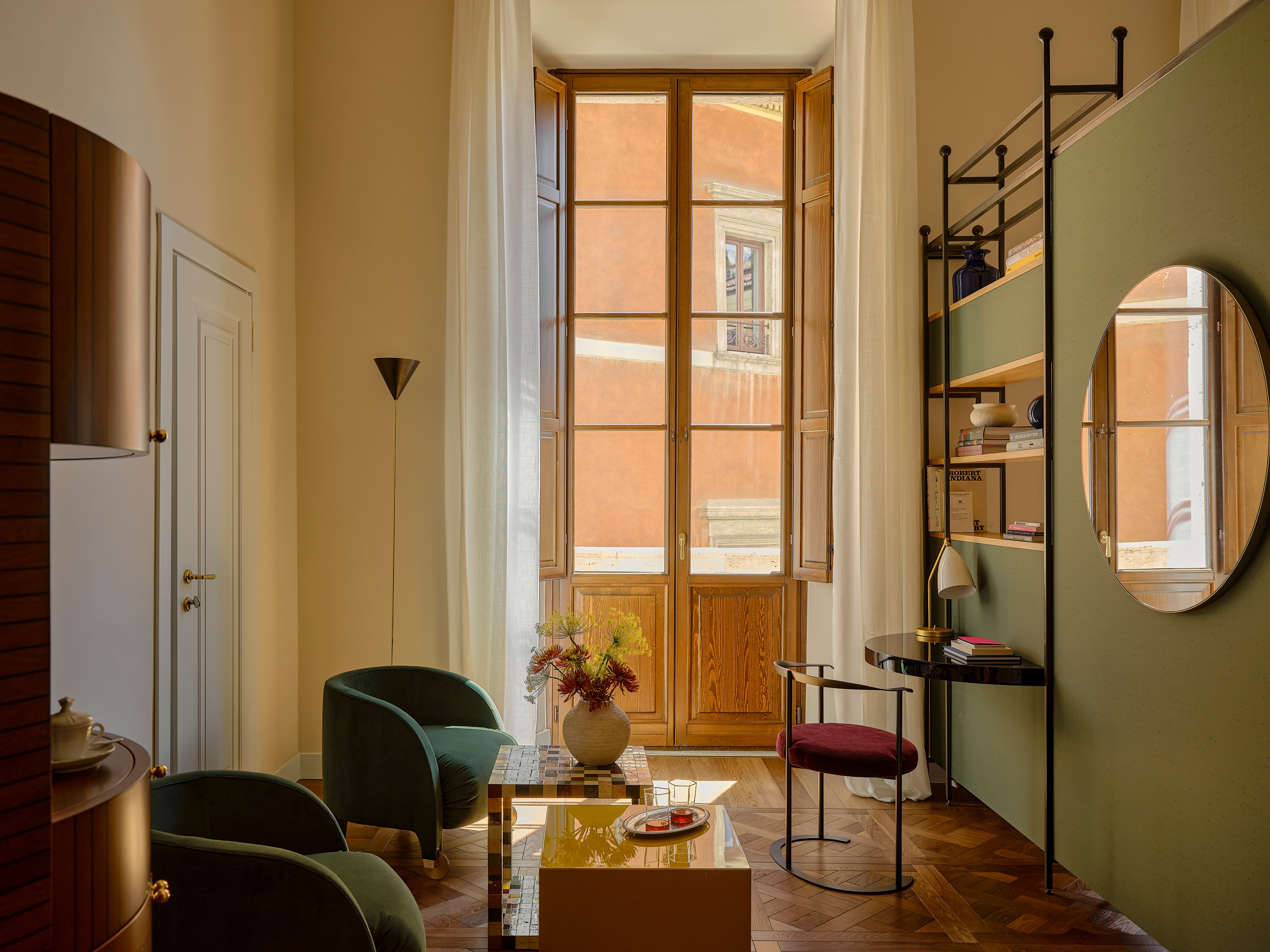 An elegant living room of a suite at Palazzo Talia with plush armchairs and vintage furniture with floor-to-ceiling wooden doors.