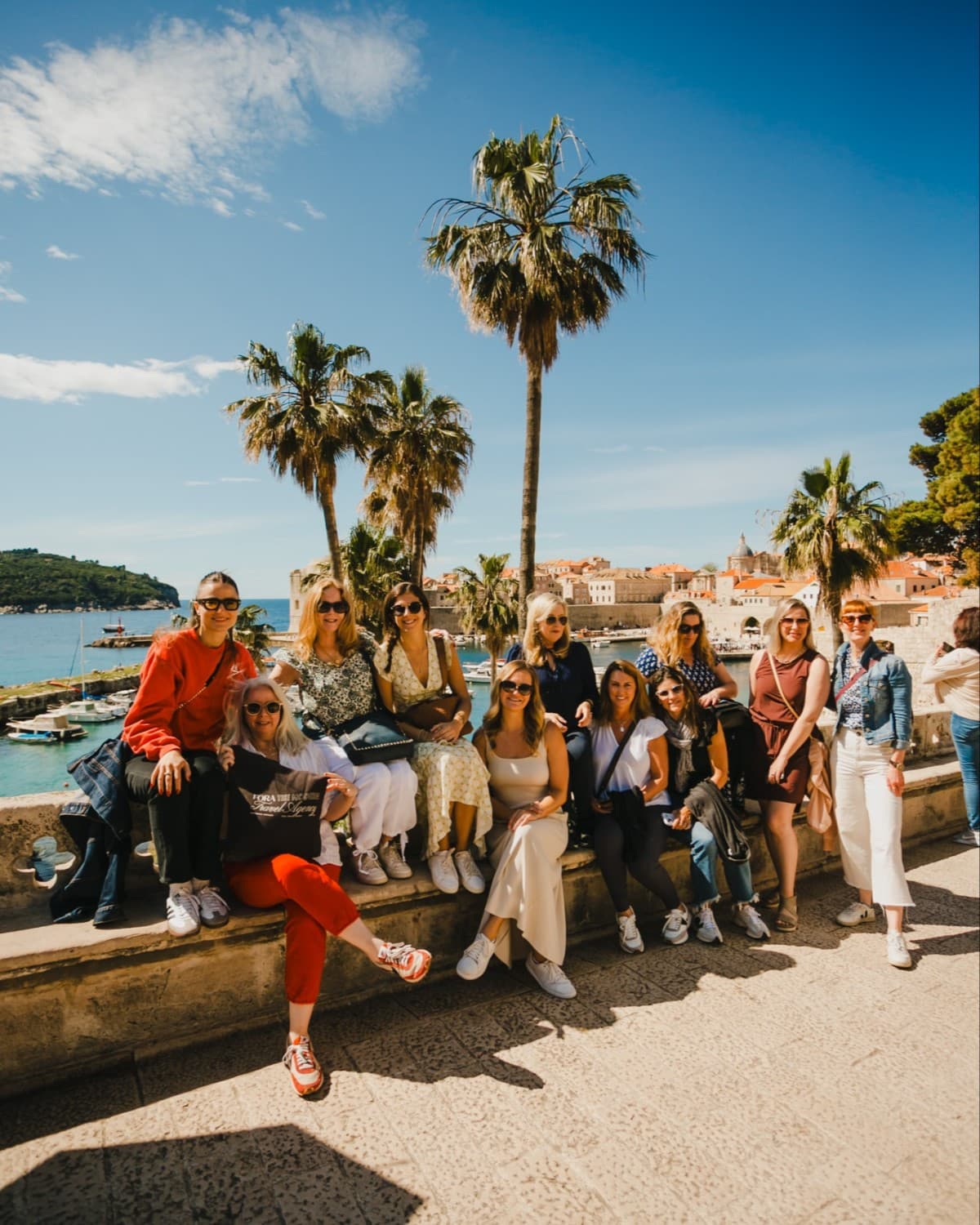 a group of people sit on a stone wall in Croatia