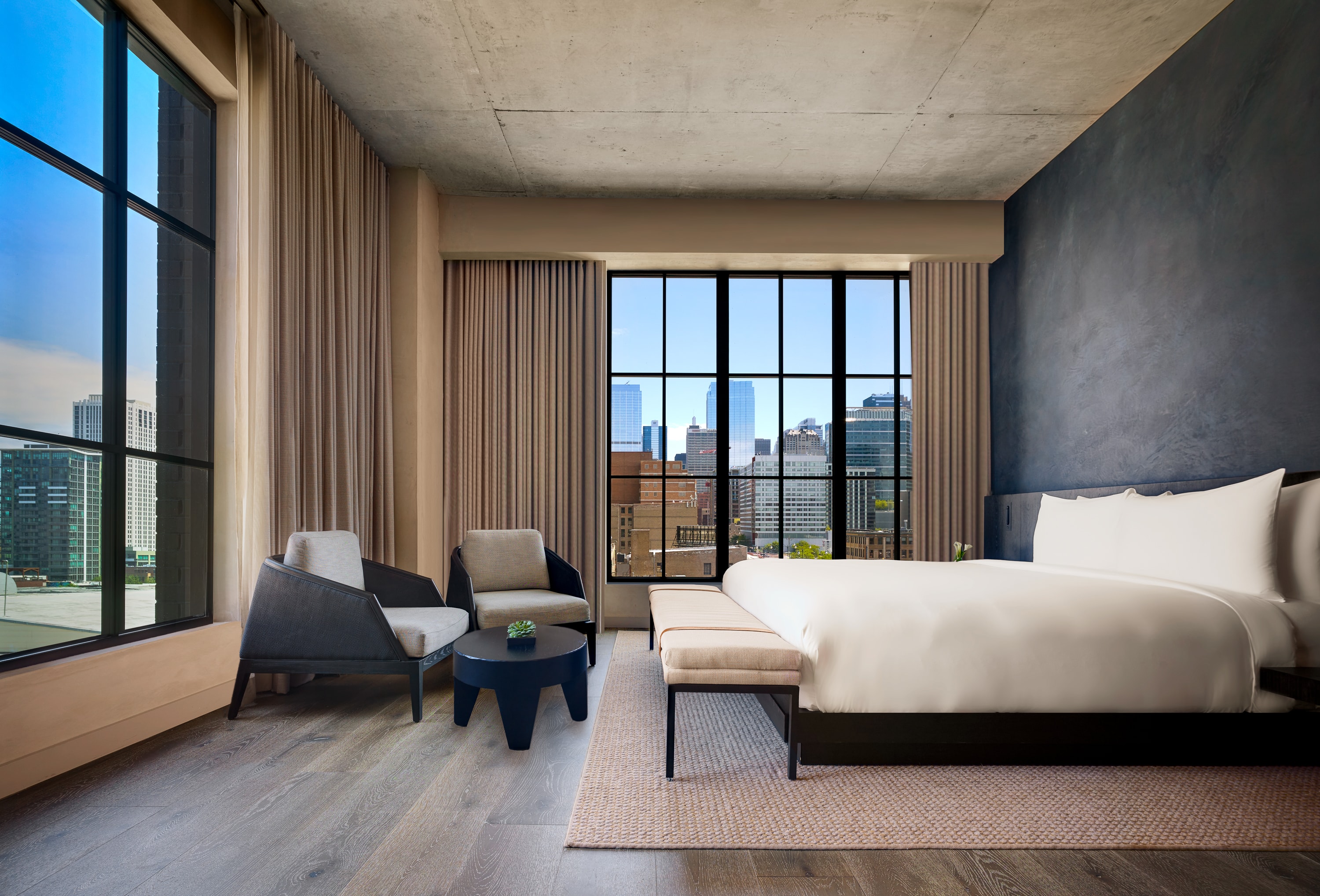 The interior of a hotel room at Nobu Hotel Chicago with a sleek asthetic, wood flooring and large windows.