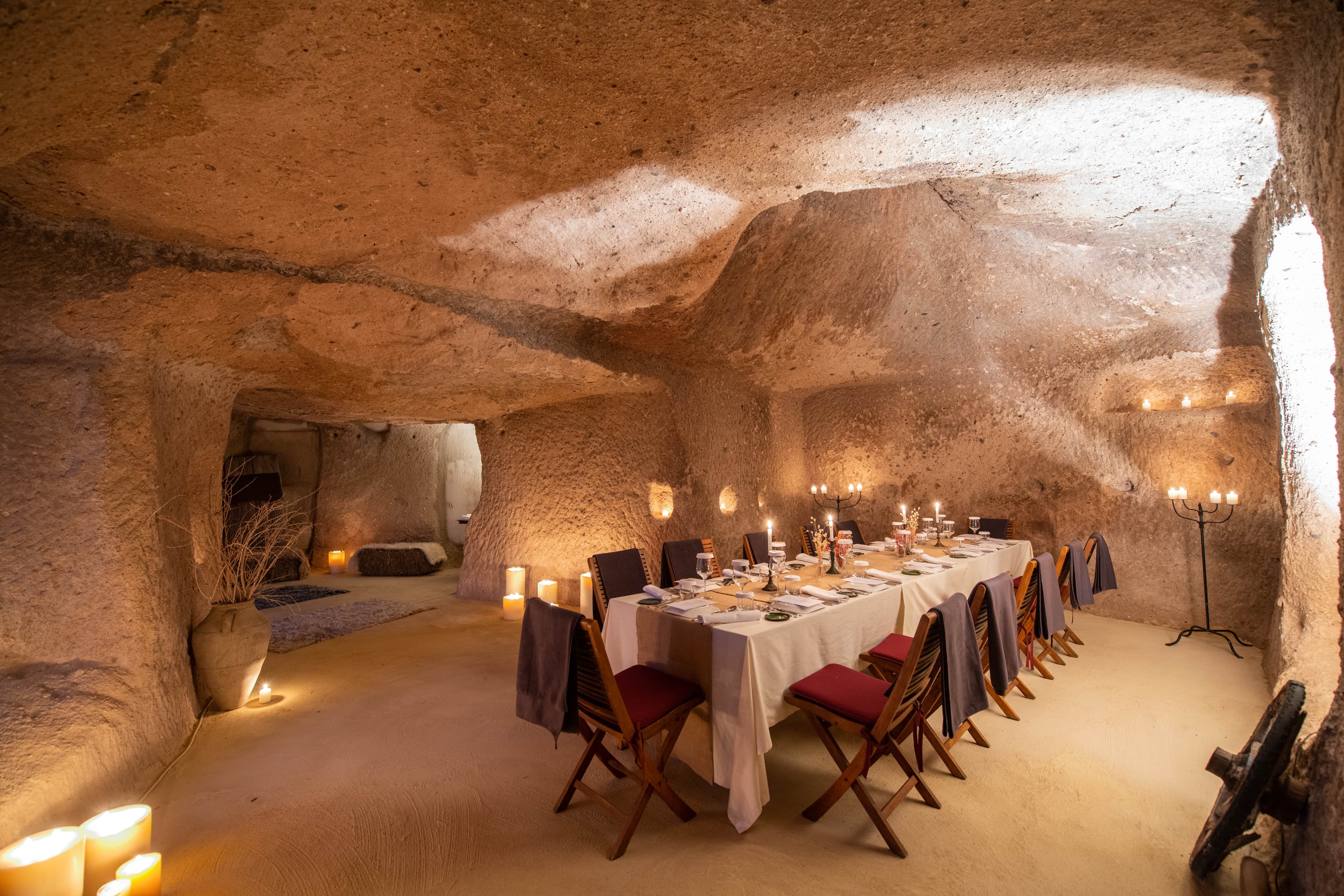 A view of a cave with an private dining setup with warm lighting and candles.