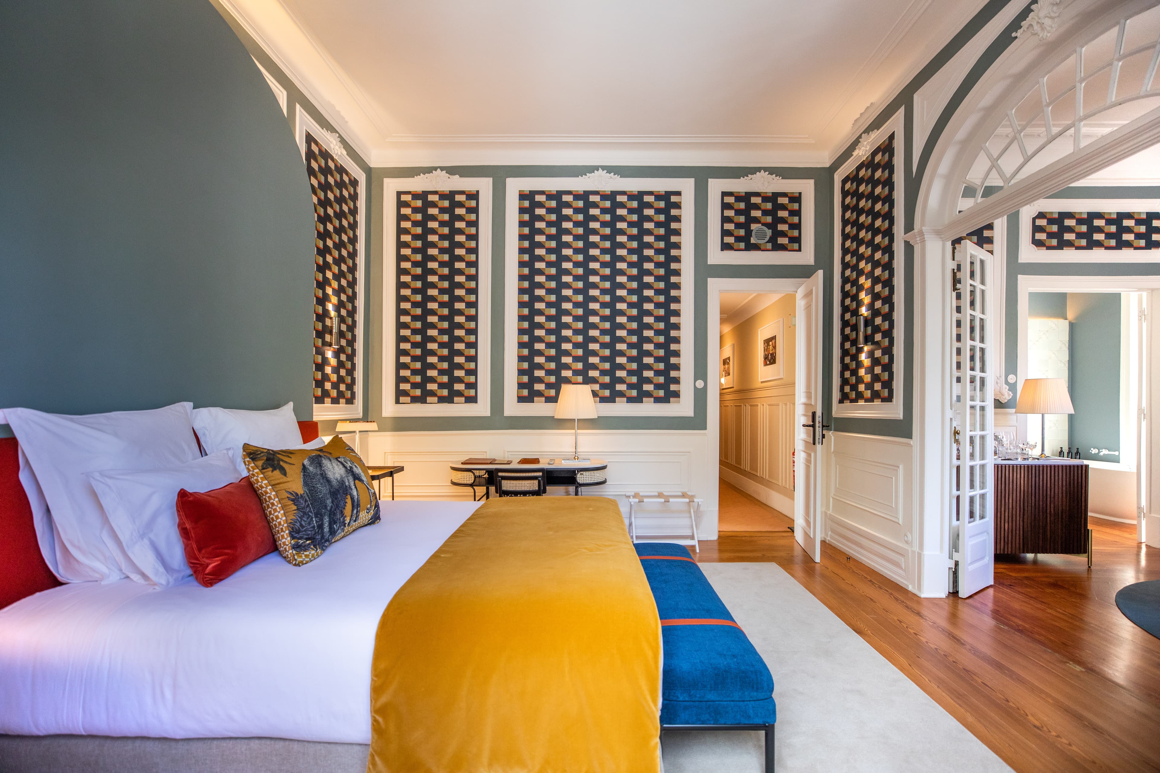 A hotel room at Sublime Lisboa with colorful bedding and furnishings and a lounge area.