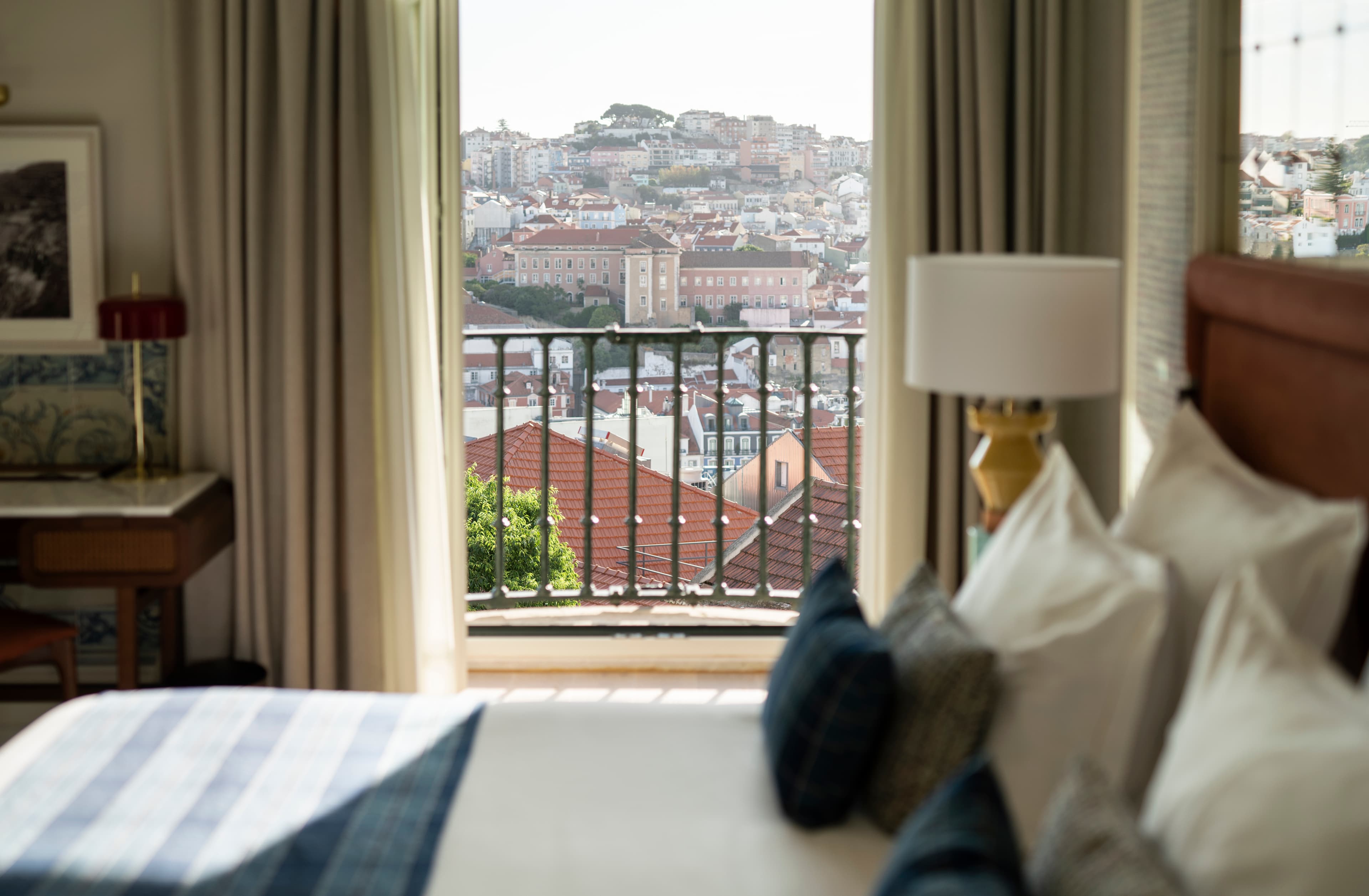 A view of a hotel room with a balcony overlooking Lisbon.