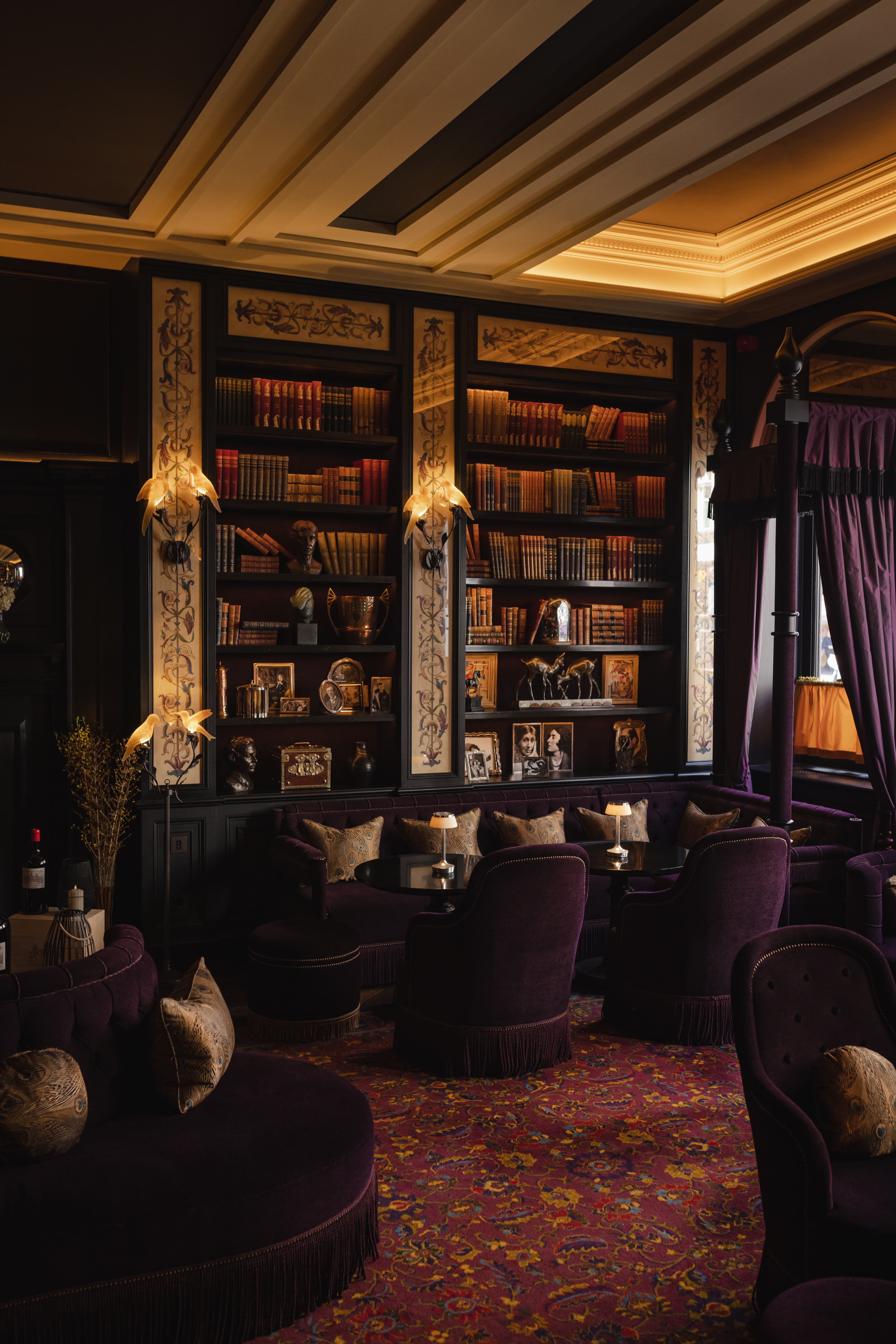 Bar area at L'oscar London with plush, purple furnishings and bookshelves.