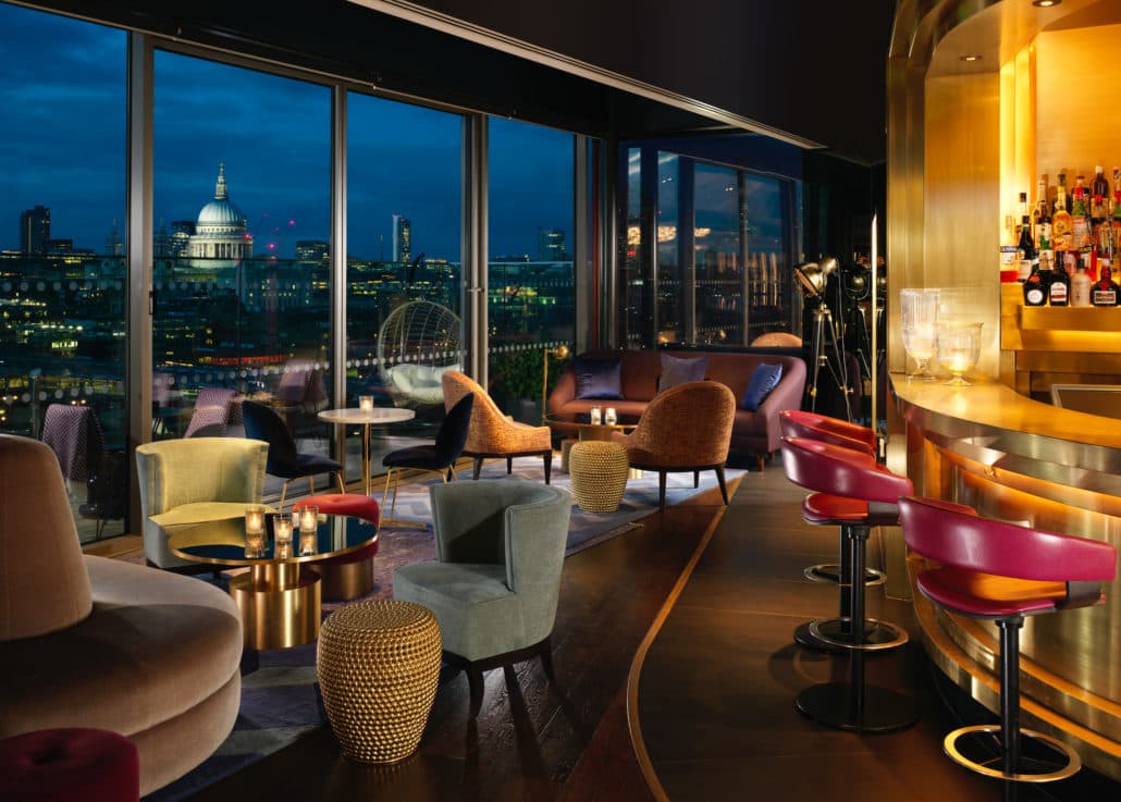 A view of the bar at night at Sea Containers, London with view of the city skyline through the windows.